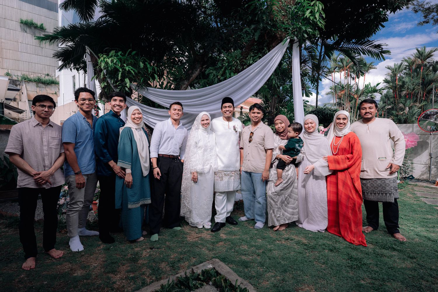 Group of family and friends posing together outdoors at a traditional Muslim wedding celebration.