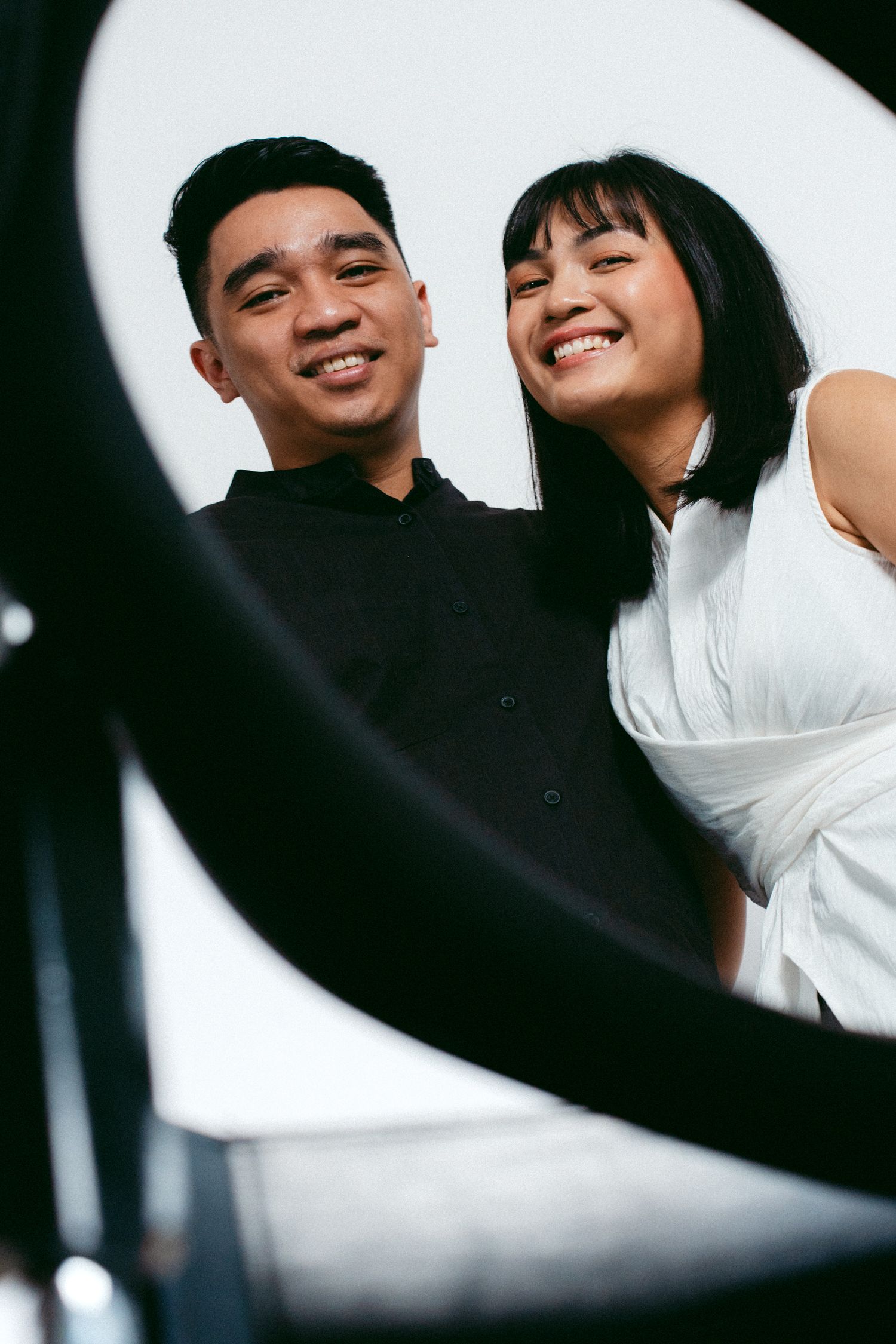 A happy couple photographed from below against a bright white background through a creative frame.