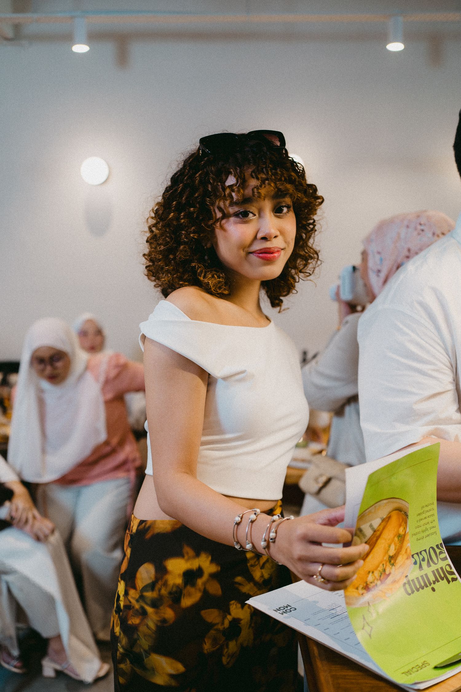 Student in casual attire holds a book at an indoor event.