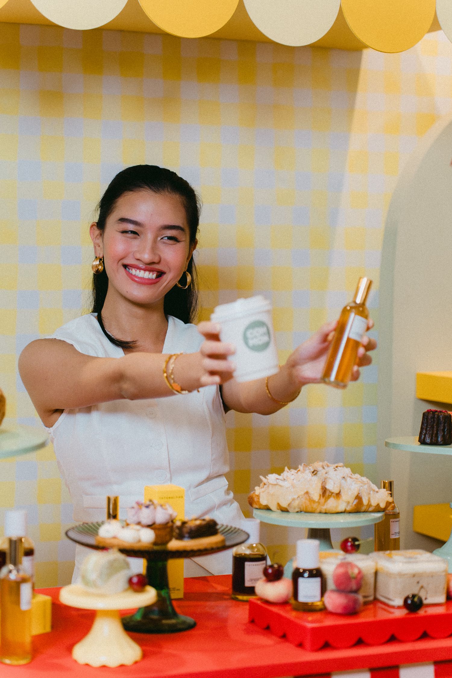 Server presents drinks and desserts at a yellow-themed cafe counter.