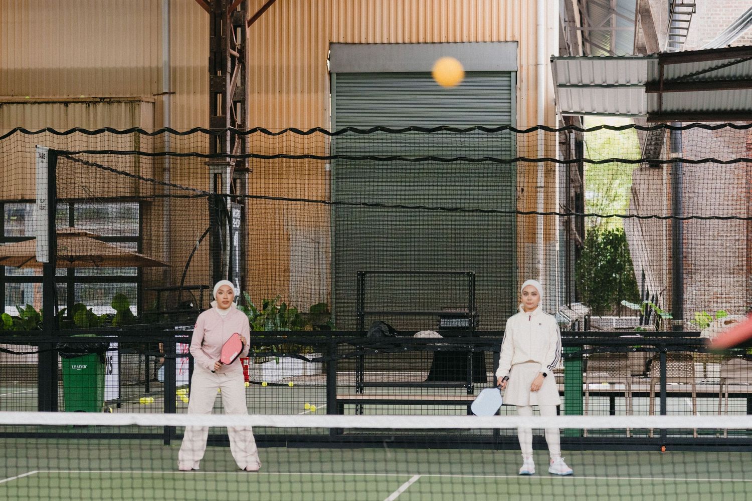 Tennis players practicing serves and volleys on an outdoor court during a training session.