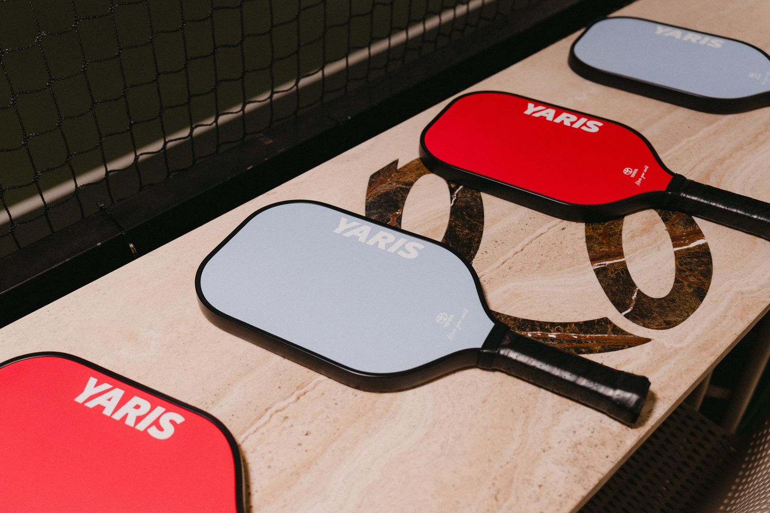 A collection of red and white sunglasses laid out in a row against a dark background.