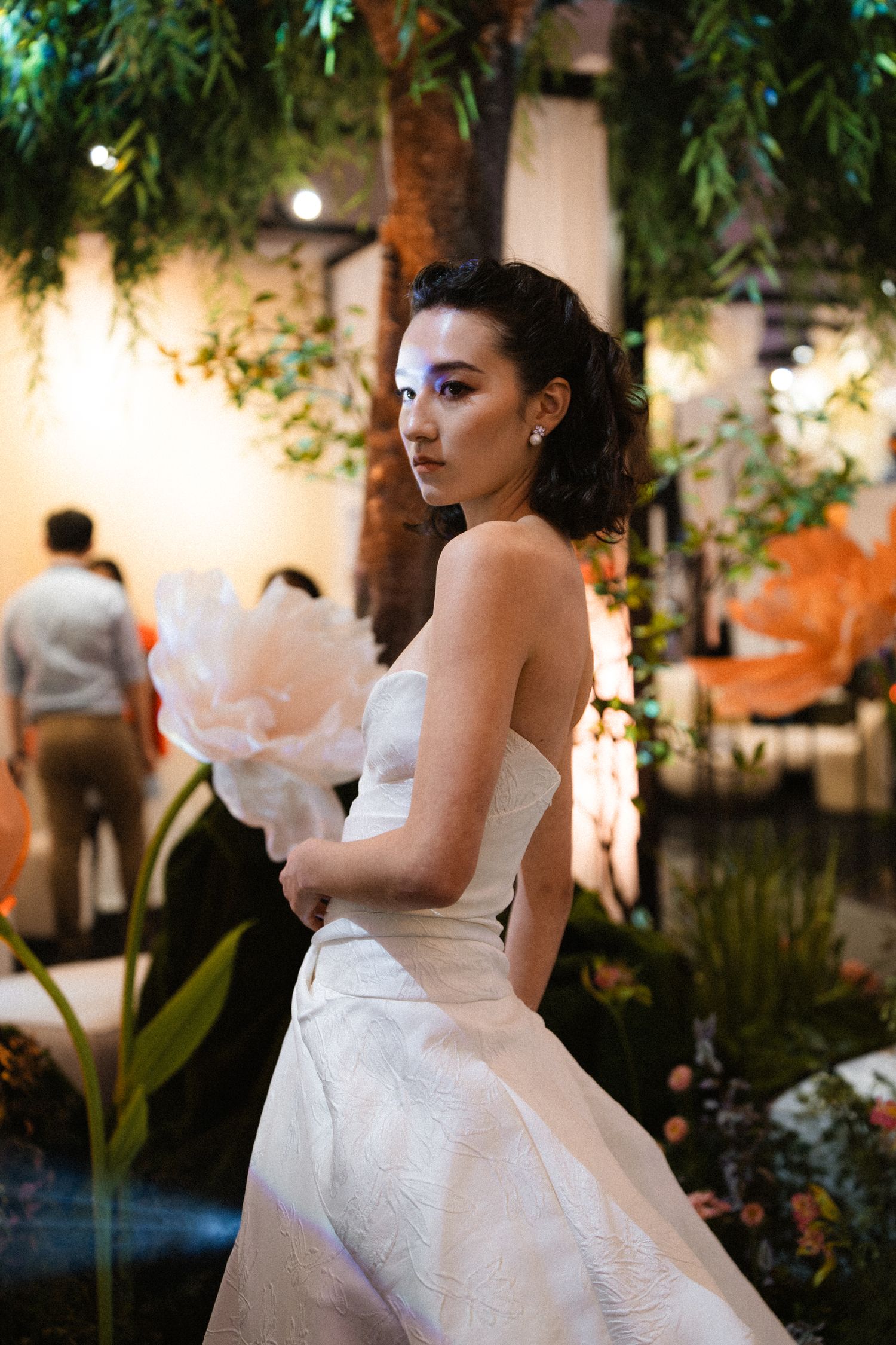Wedding fashion show featuring a white strapless gown in a garden-themed setting.