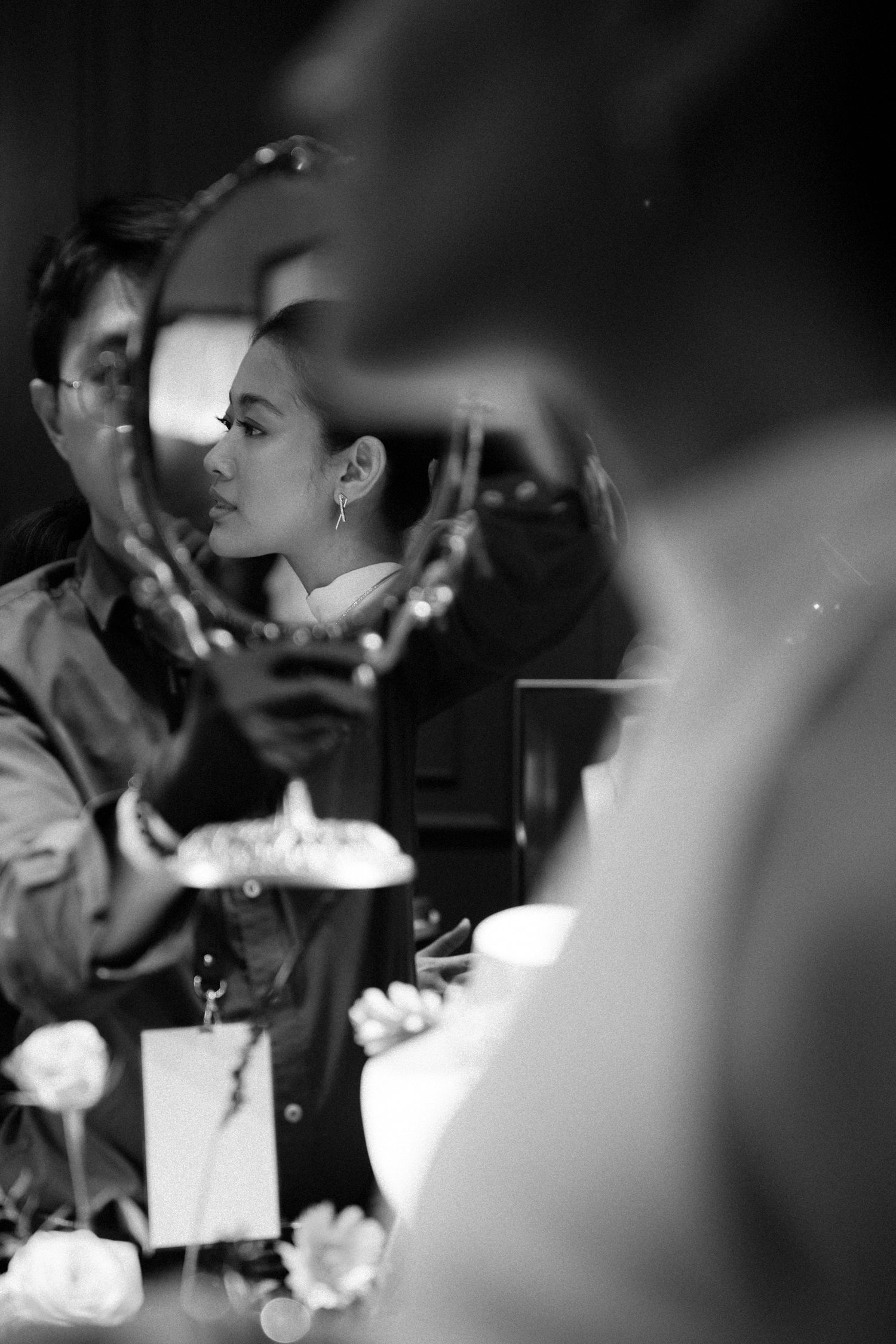 Blurred black and white photograph capturing a candid dining moment with flowers in foreground.