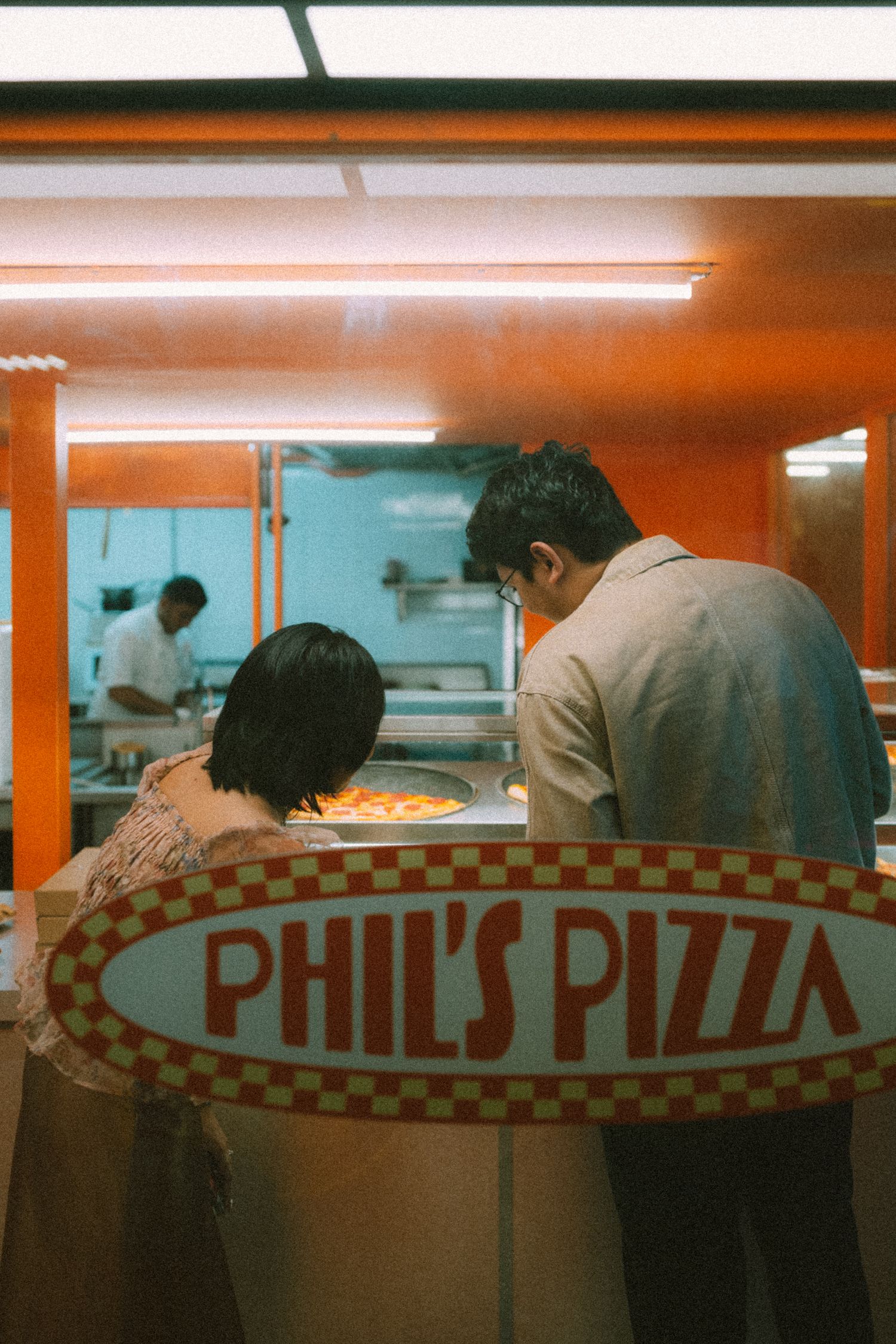 A couple enjoying dinner at Phil's Pizza restaurant counter with warm lighting.