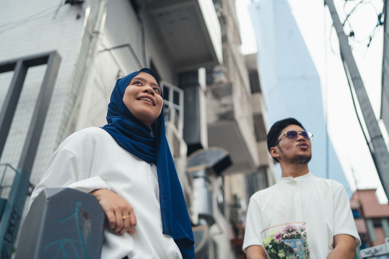 Two people in white clothing sharing joyful moment on city street.