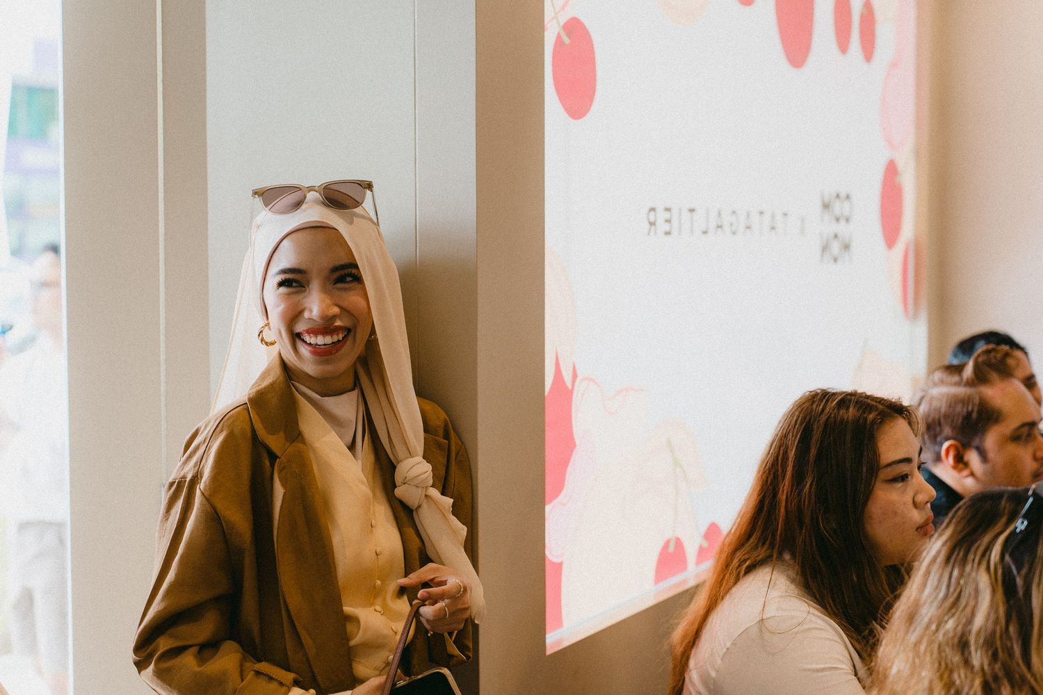People socializing in a bright modern cafe space with pink wall accents.