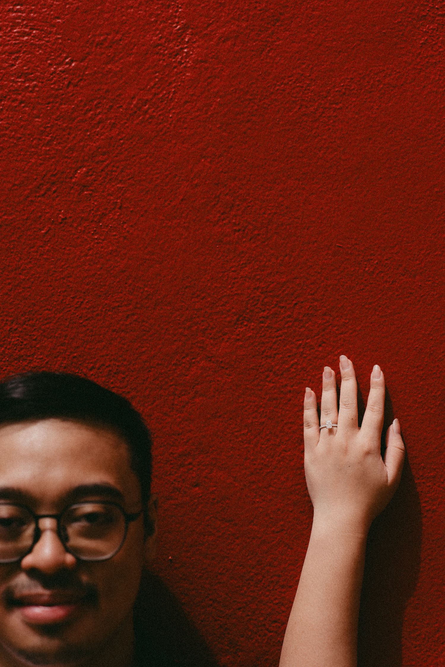 Progressive sequence of a person's hand waving against a deep red wall background.