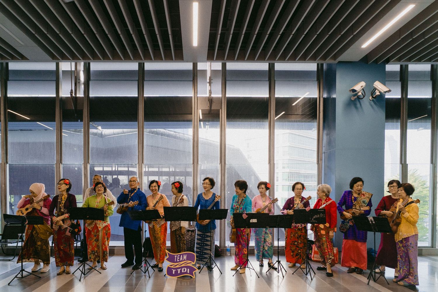 Musicians in colorful traditional clothing performing in a modern indoor space.