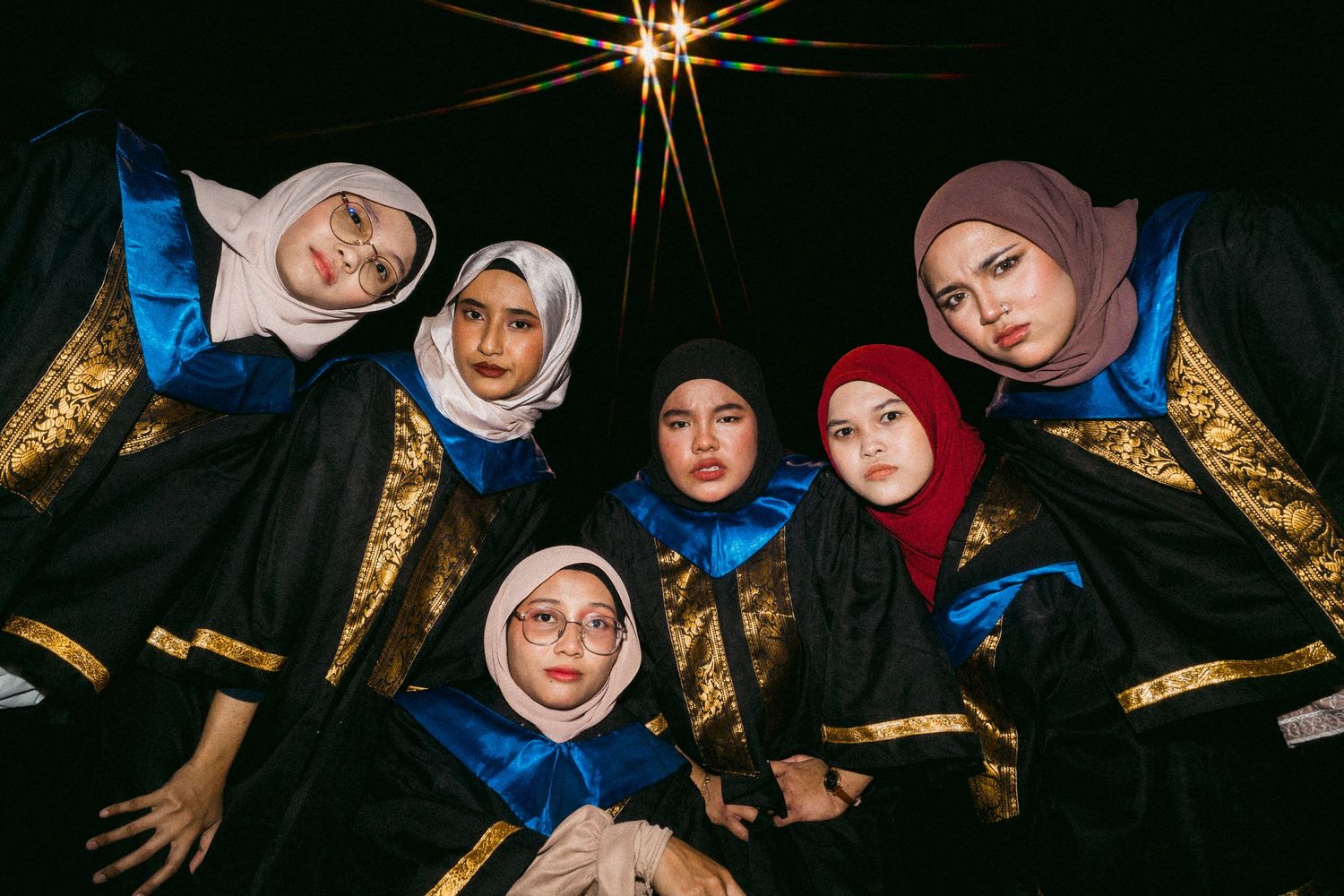 Low-angle shot of graduates in black and gold robes forming a circle.