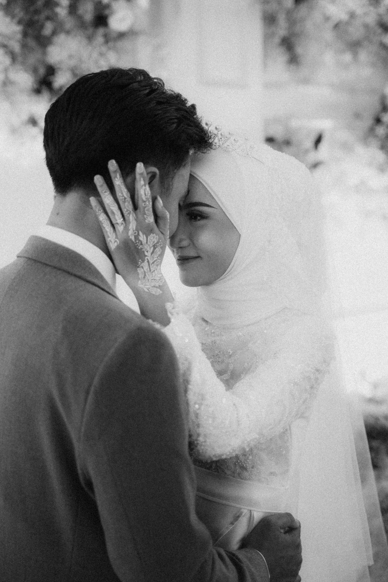 A romantic wedding moment captured in black and white showing a tender embrace through a delicate veil.