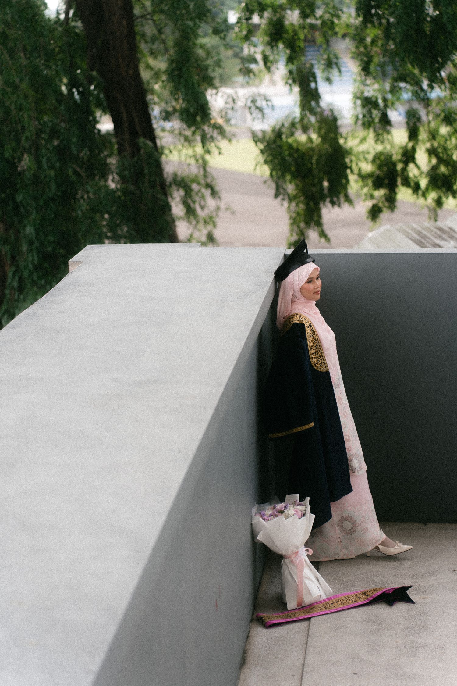 A sequence of images showing a cat's tail progressively appearing from behind a white concrete wall outdoors.