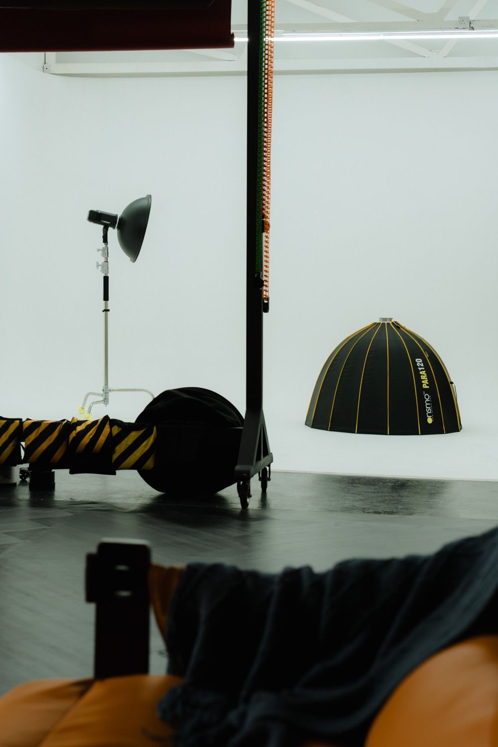 Professional photography studio setup with strobe lights, a dome softbox, and equipment on a dark stage floor.