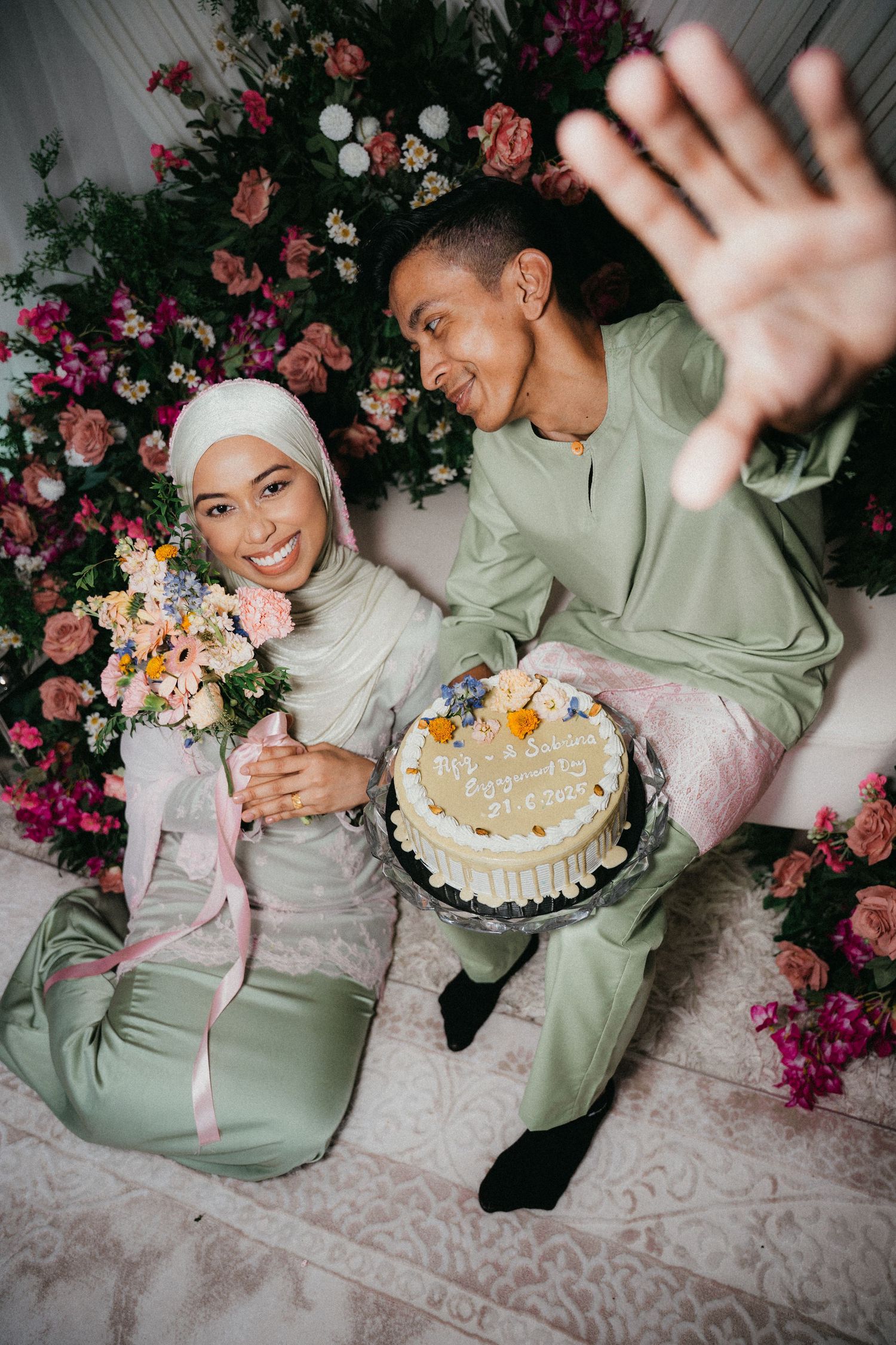 A sweet celebration moment with flowers and cake against a floral backdrop, captured in soft lighting and mint green hues.