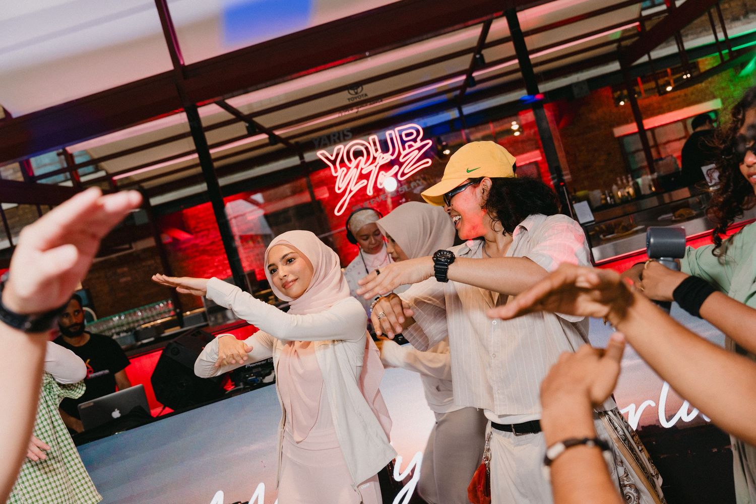 People dancing and having fun at a nightclub with red neon lighting and energetic atmosphere.