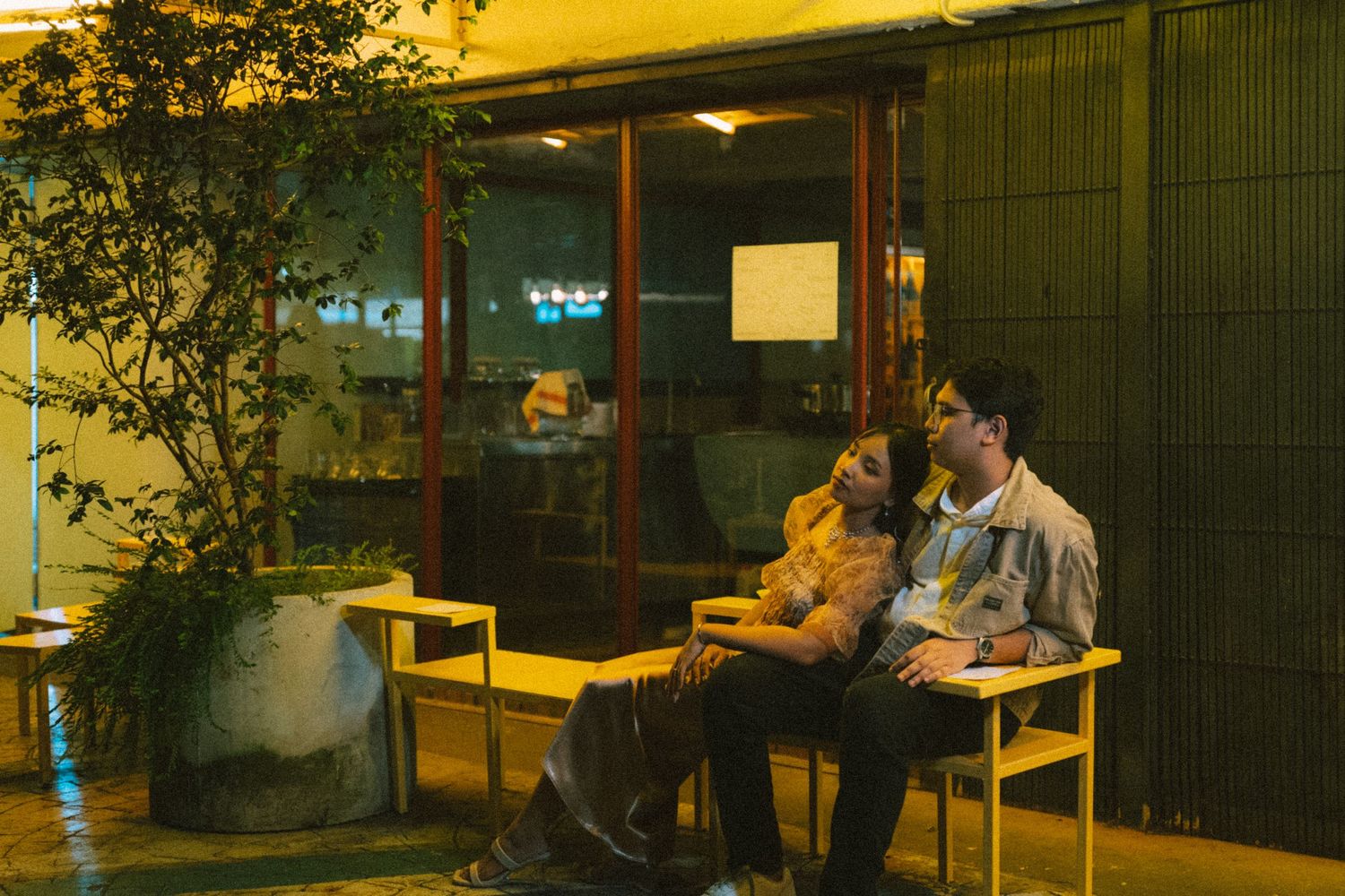 Couple relaxing on outdoor chairs at night under warm lighting.