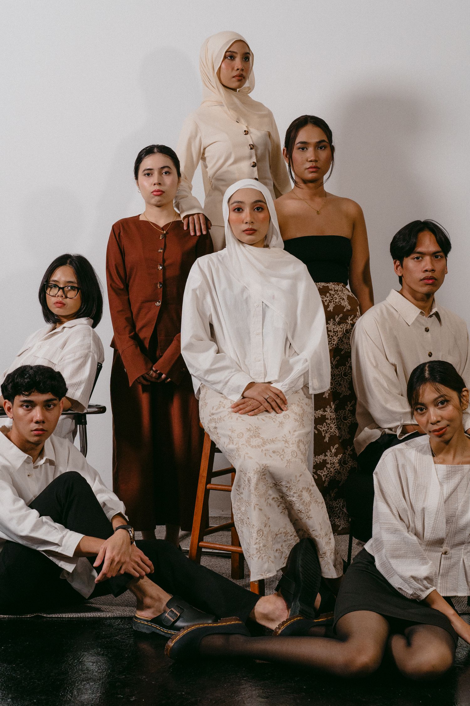Studio fashion portrait of group in coordinated neutral-toned outfits against white backdrop.