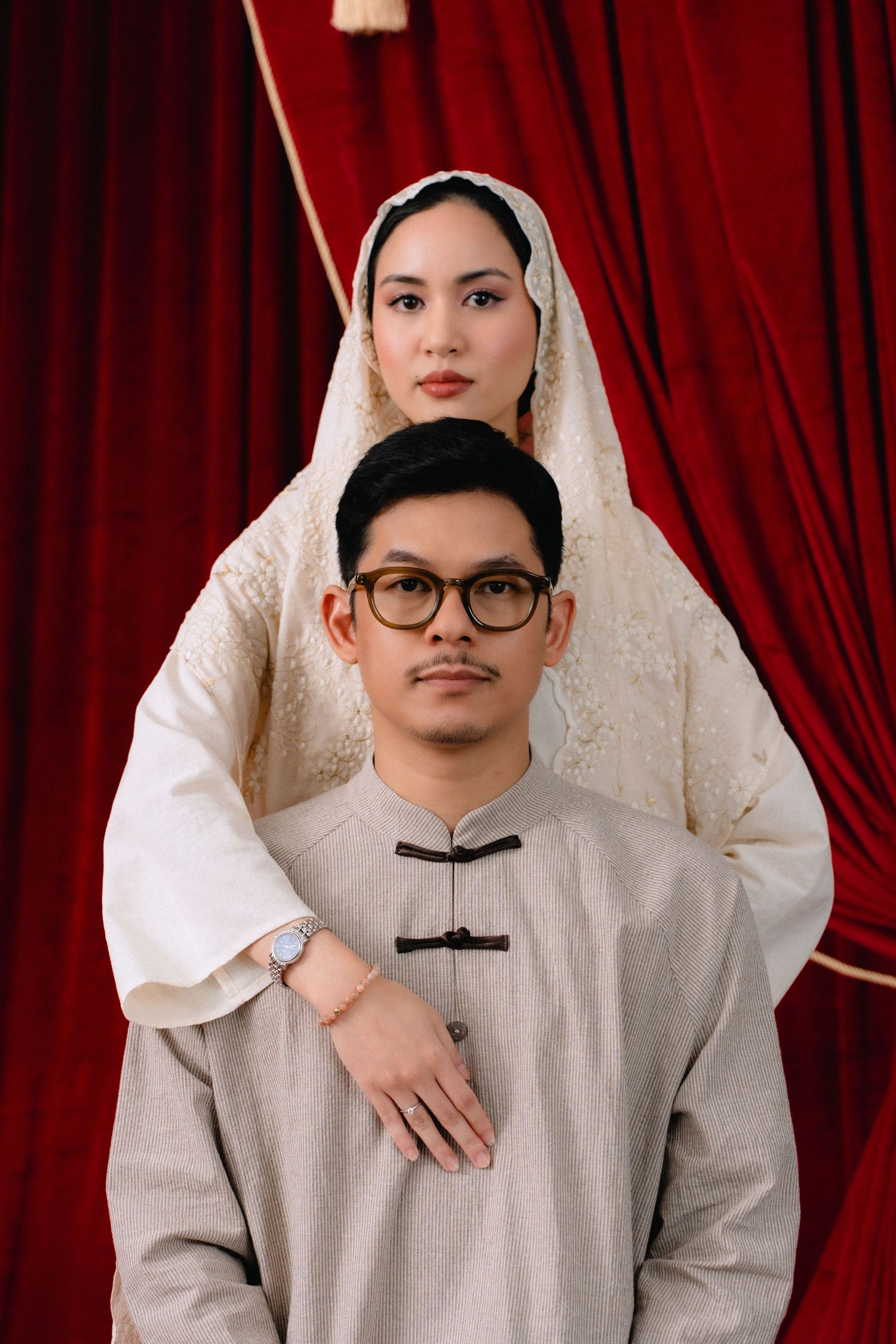 A person in a white hijab and glasses poses against a red curtain background in a series of similar shots.