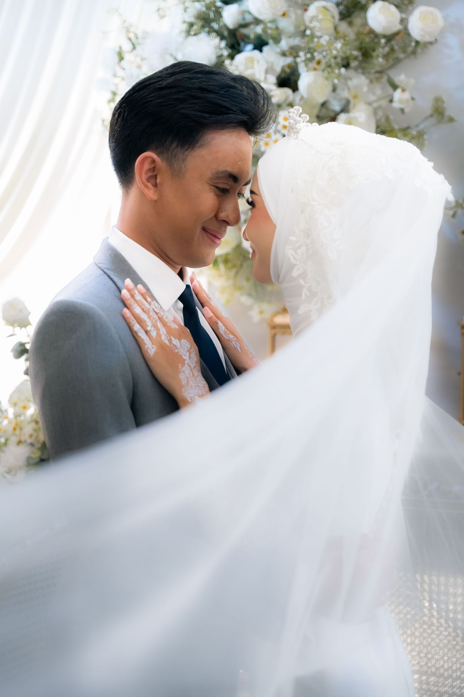 A romantic wedding portrait series showing tender moments between newlyweds surrounded by white floral decorations.