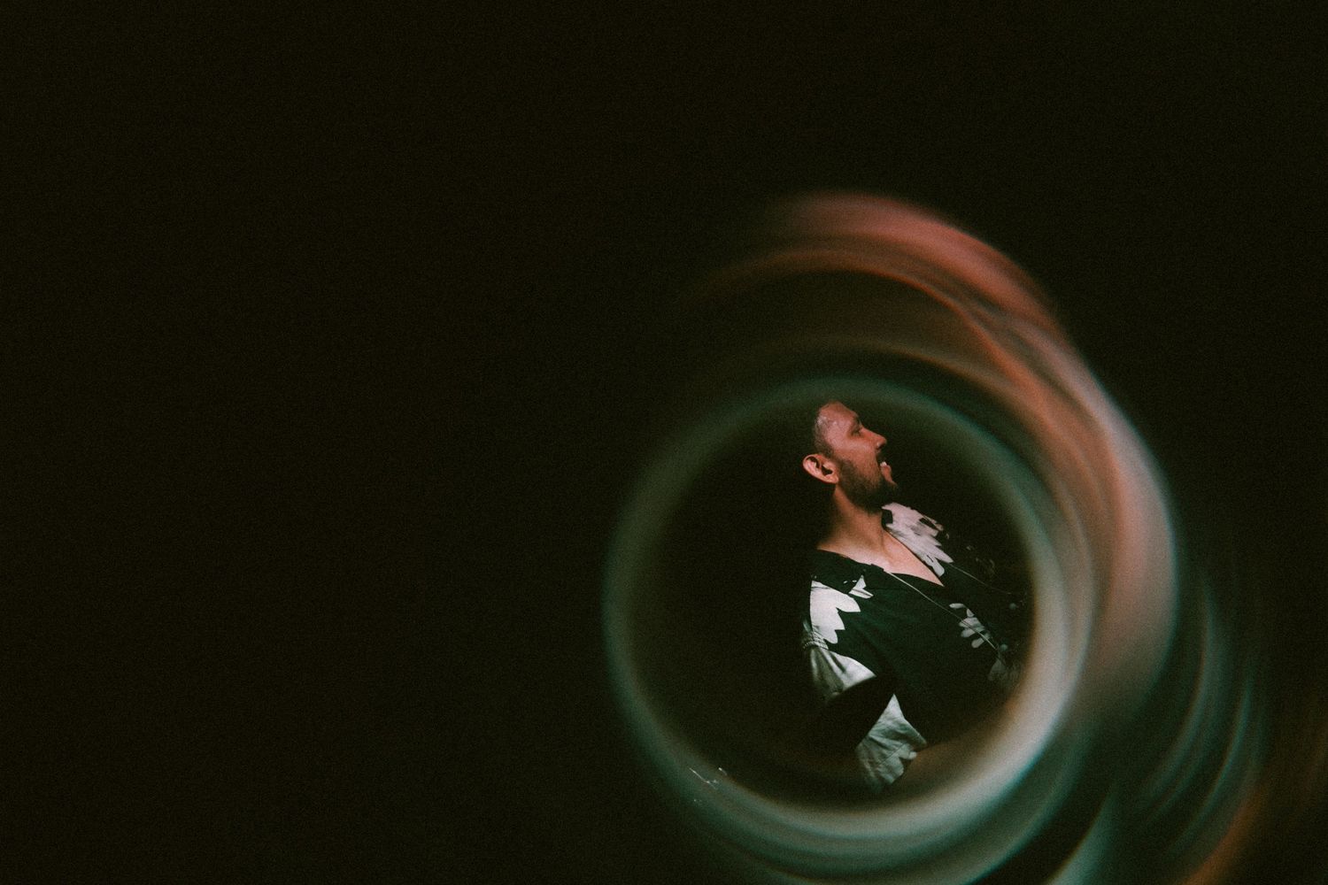 Artistic spiral motion blur effect creates a dark tunnel composition with a figure in black and white clothing.