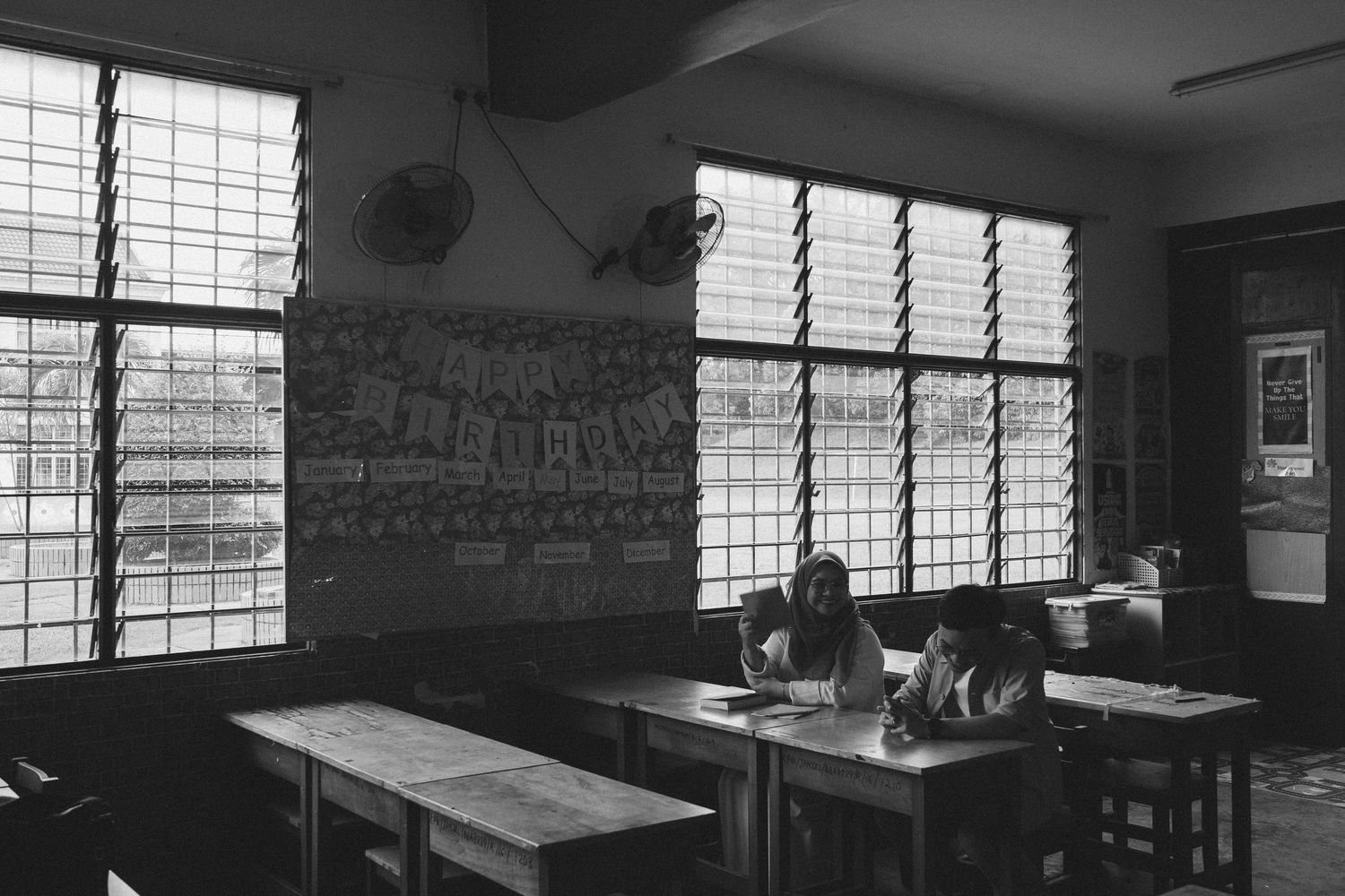 Black and white photo of classroom interior with louvered windows.