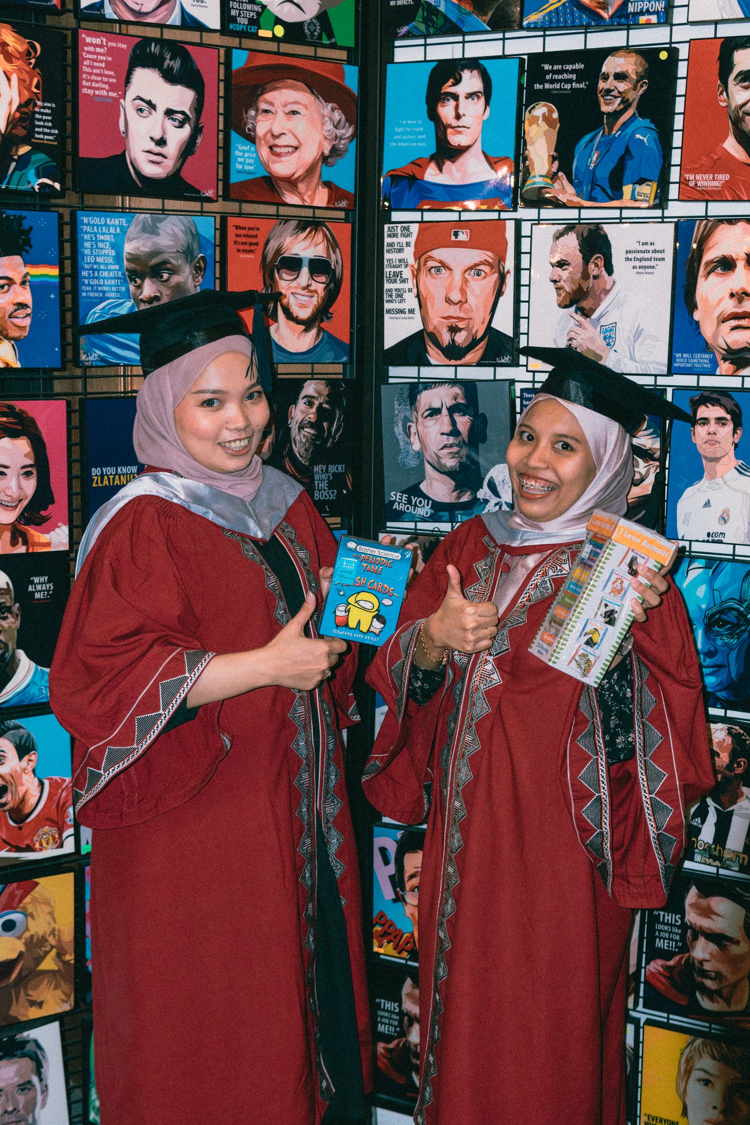 Graduates pose with snacks in front of wall of celebrity magazine covers.