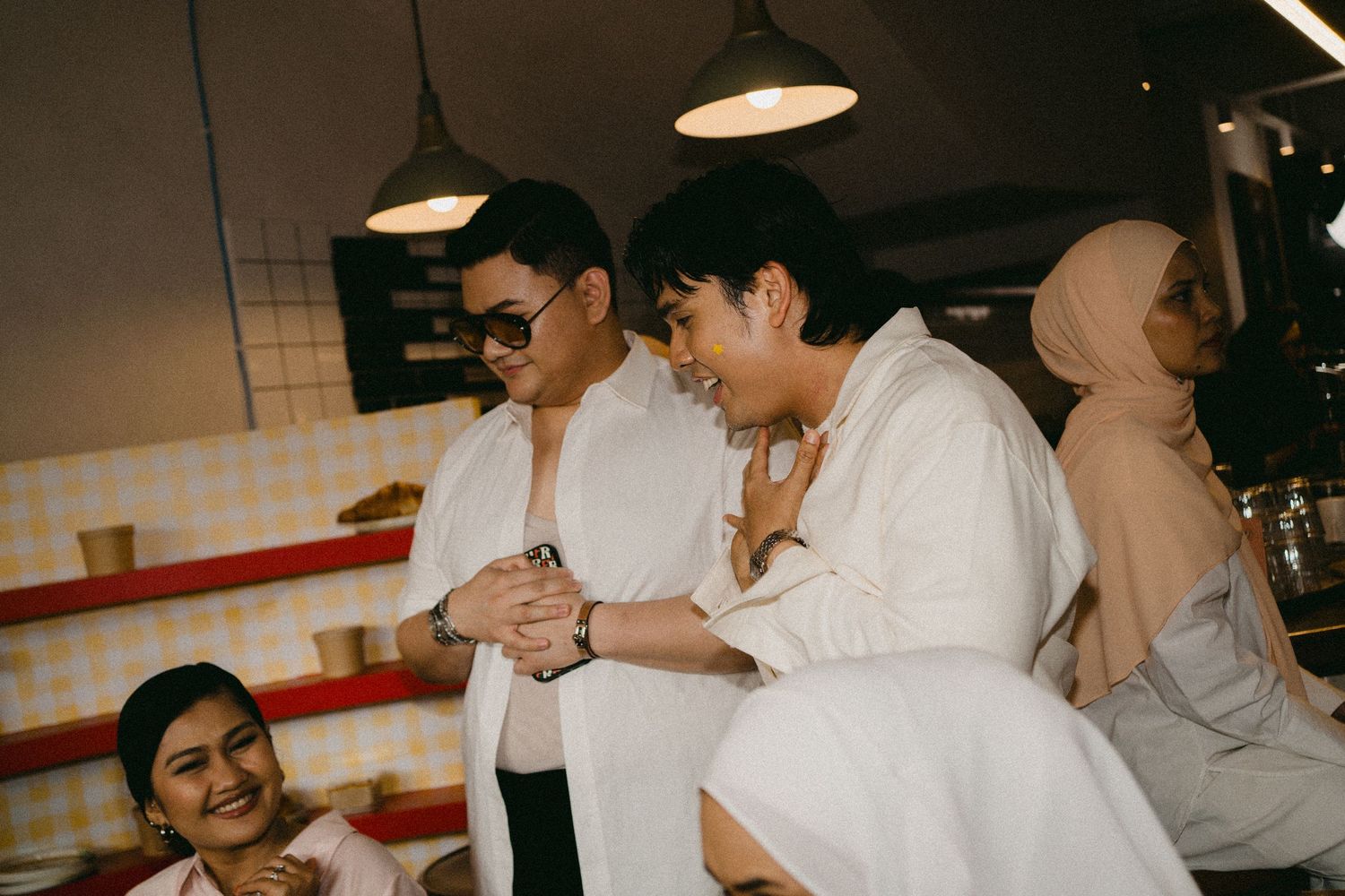 Group of people in white outfits gathered at a casual indoor setting.