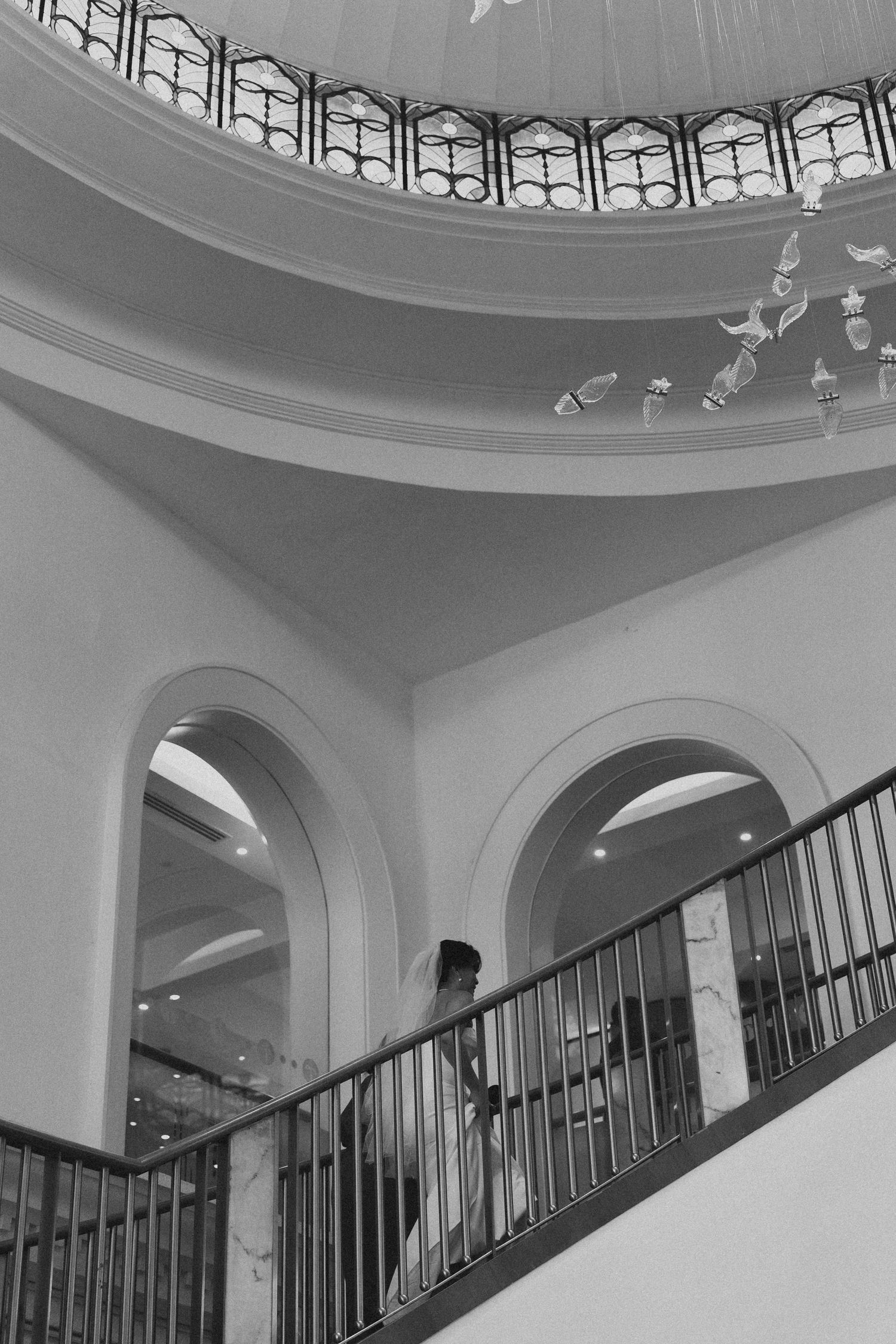 Black and white architectural interior photo showing ornate curved ceiling details and an elegant staircase railing.