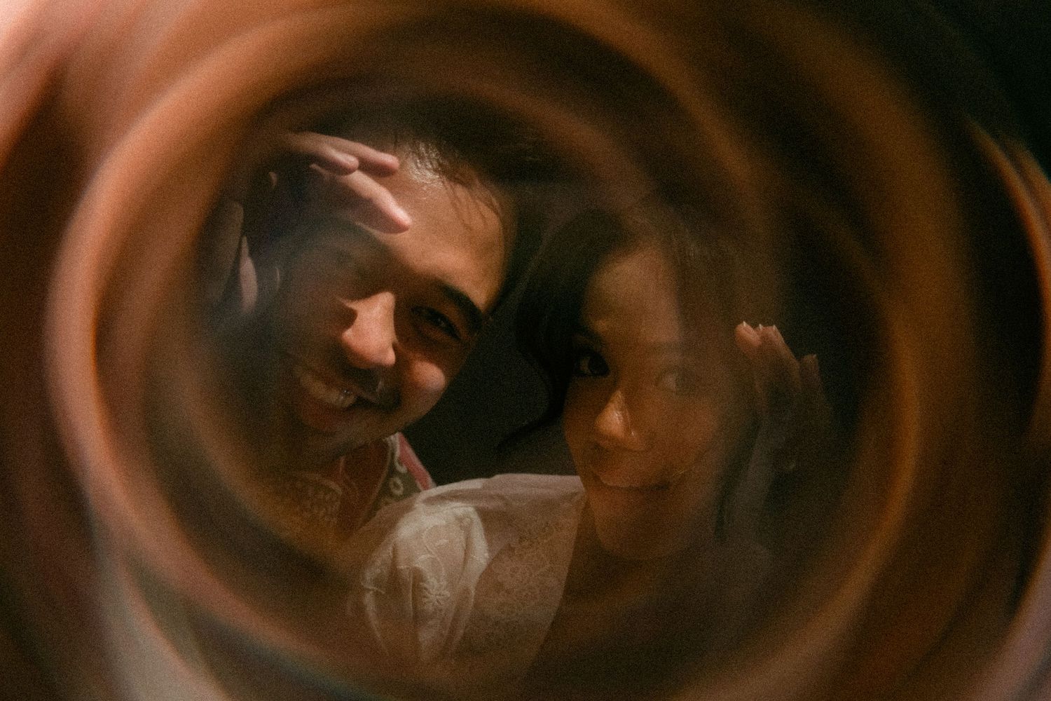 Two people seen through a circular lens with a warm brown swirling vignette effect.