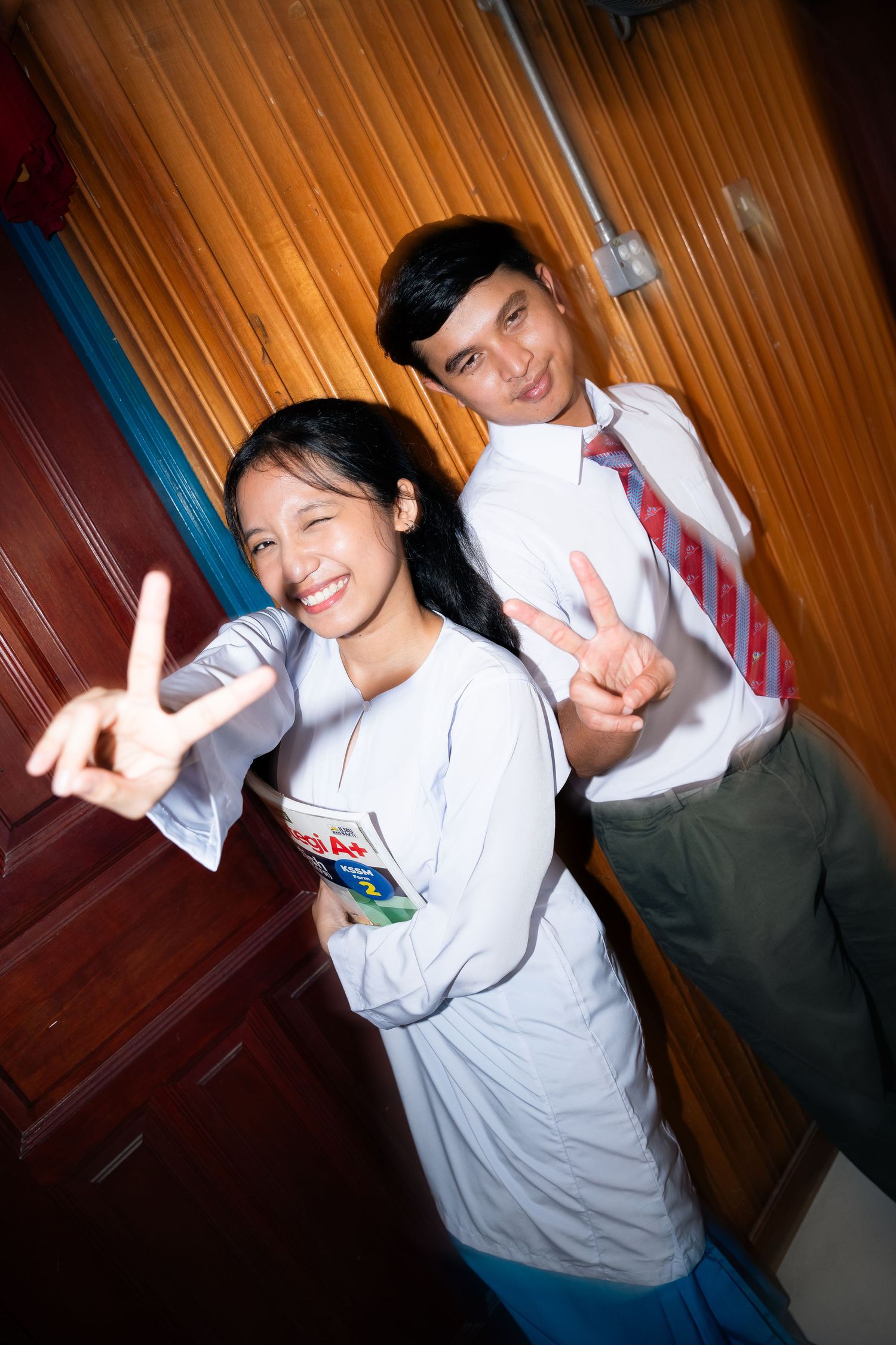 A series of candid poses showing people making peace signs in a dimly lit room with wood paneling.