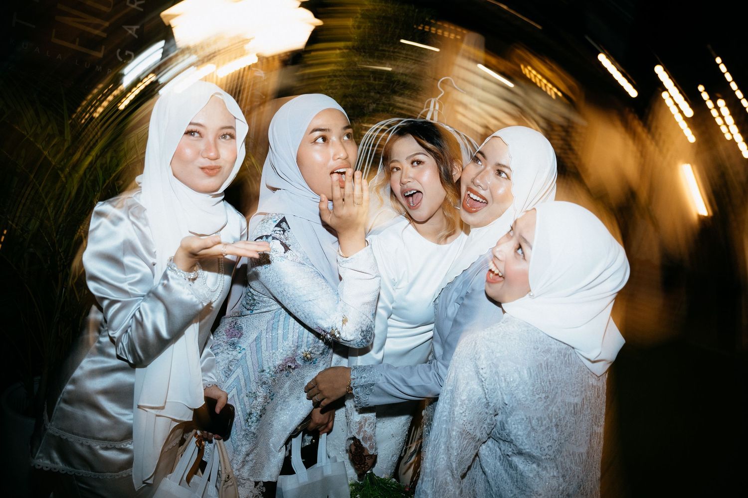 A group posing together wearing matching white outfits in a dimly lit setting.