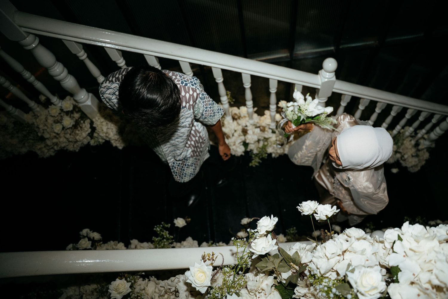 Workers harvesting and inspecting mushrooms on shelves at a commercial mushroom growing facility in low light.