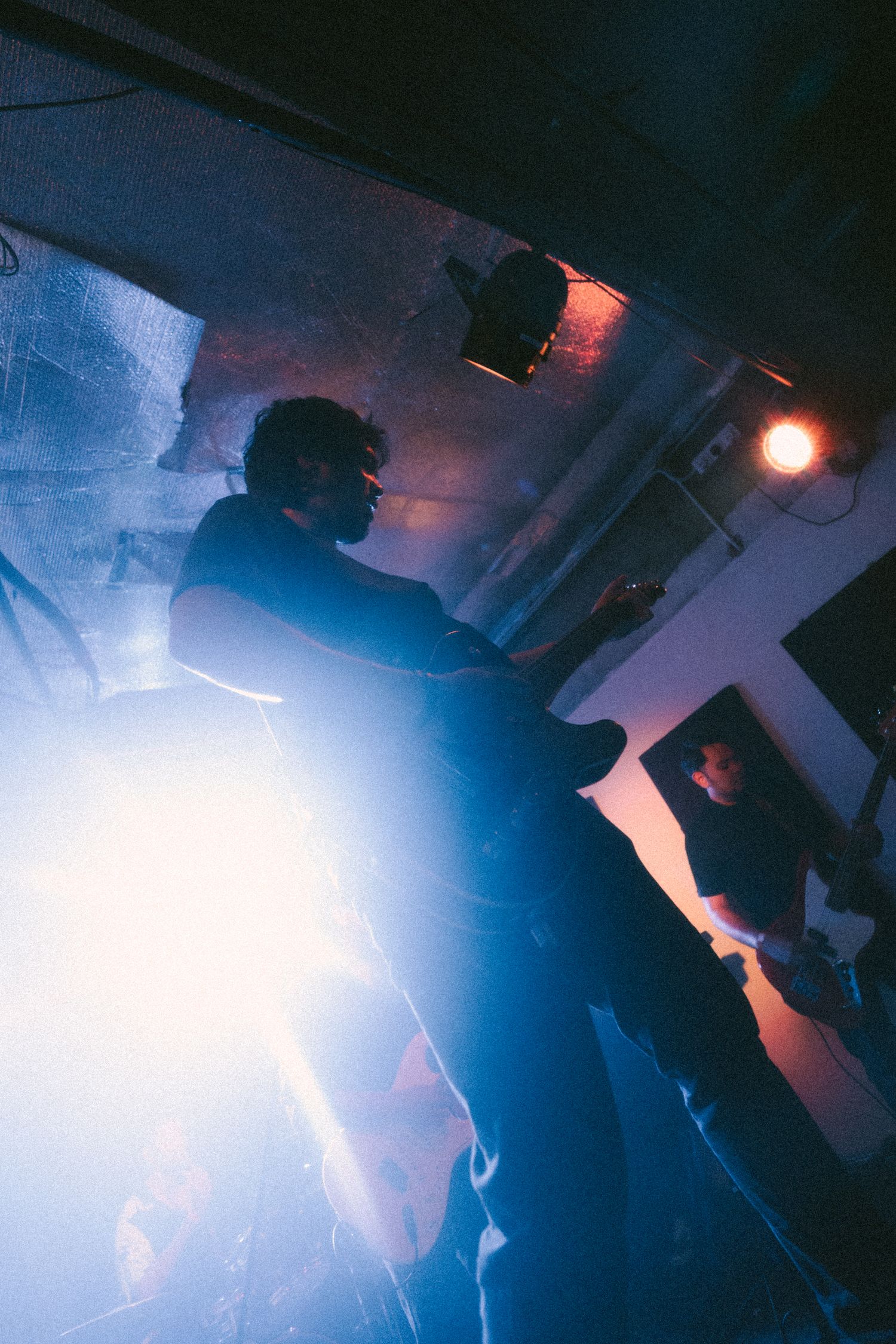 A series of overlapping silhouettes in dark lighting with bright blue and red lights create a moody atmospheric scene.
