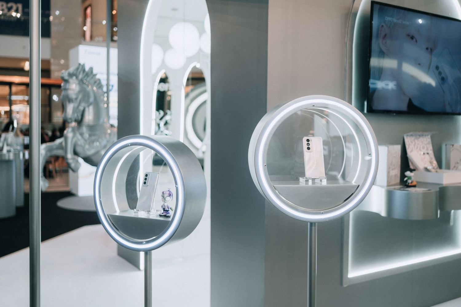 Modern retail display featuring illuminated circular product stands with white tech devices.