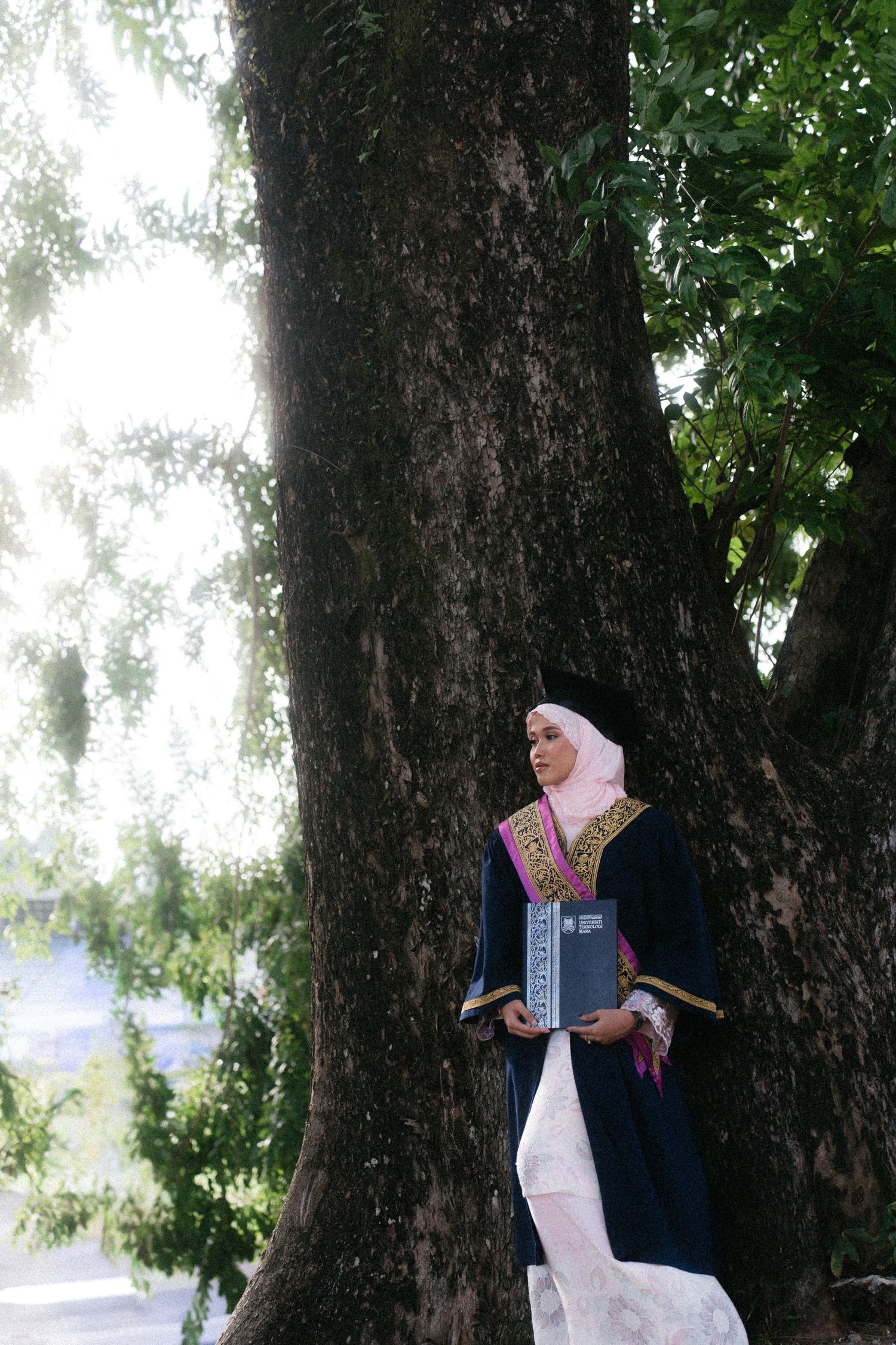 A couple shares a romantic moment under tall trees during their outdoor wedding photoshoot.