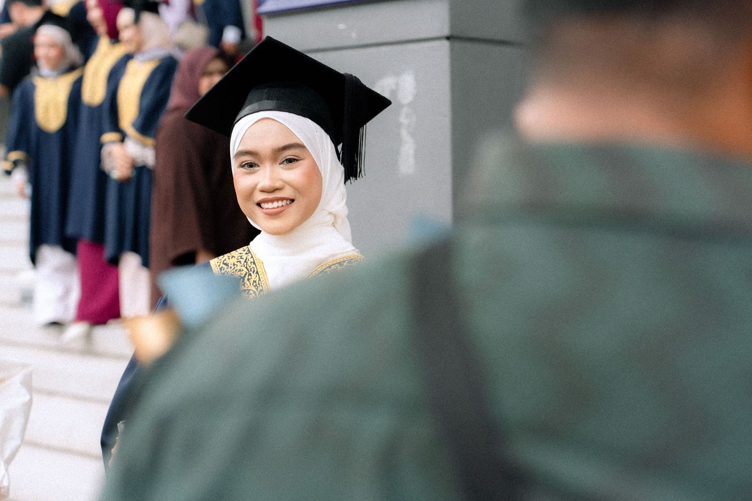 A couple in traditional wedding attire exchanges joyful glances during an outdoor ceremony.
