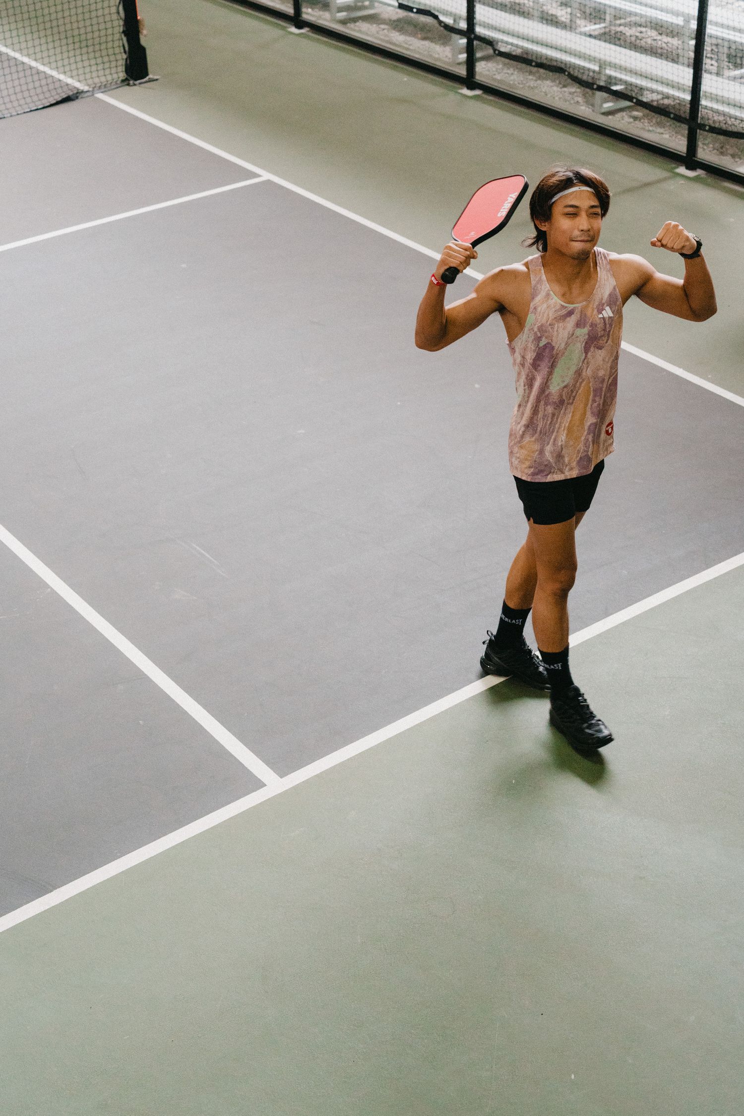 A sequence of five action shots showing a tennis player sliding and reaching for a low shot on an indoor court.