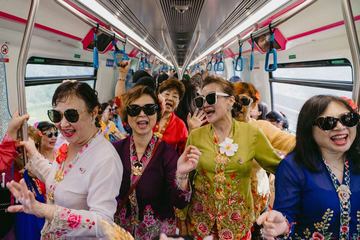 Festive group wearing sunglasses and bright traditional clothing celebrating on public transit.