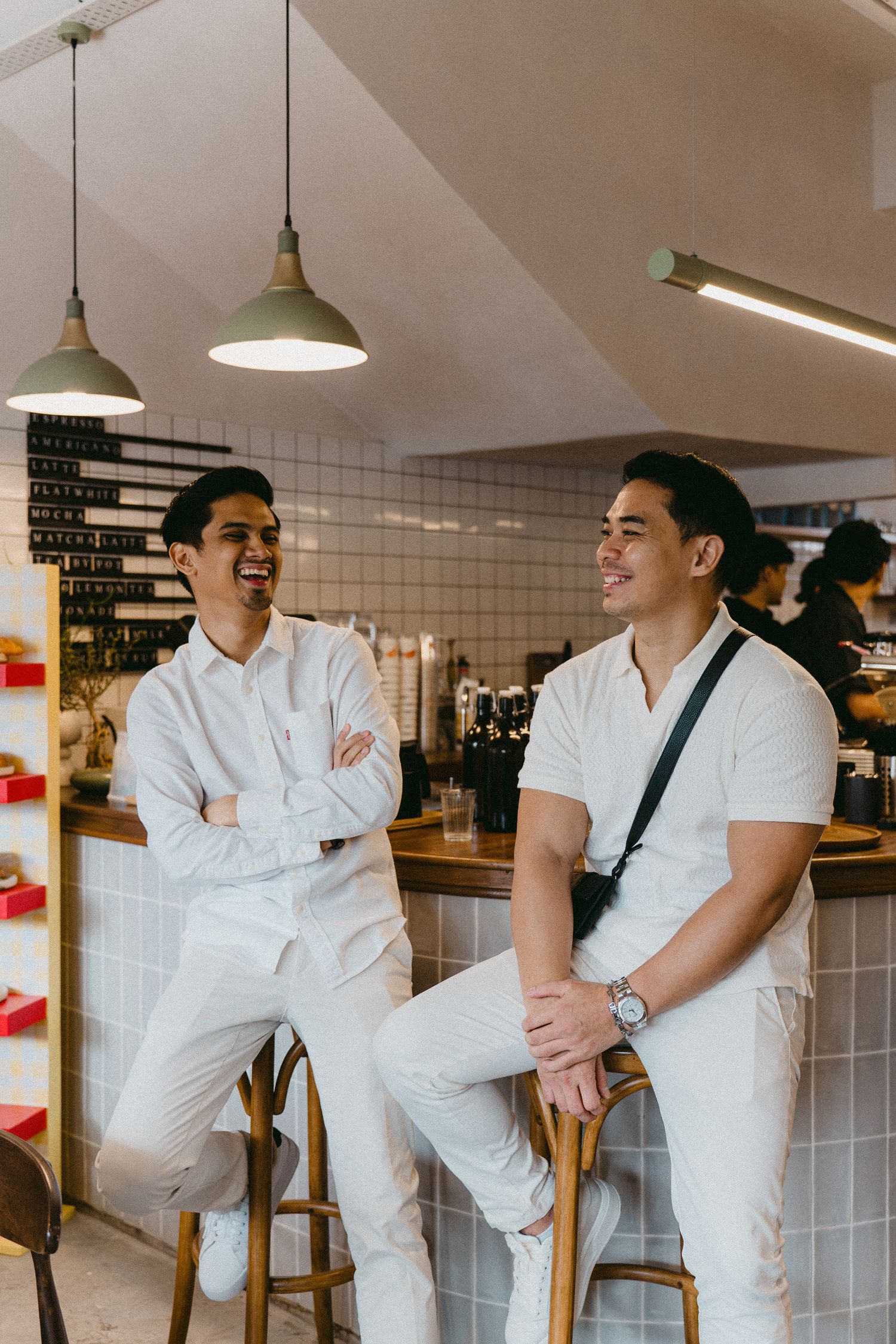 Two people in white uniforms having casual conversation at cafe counter.