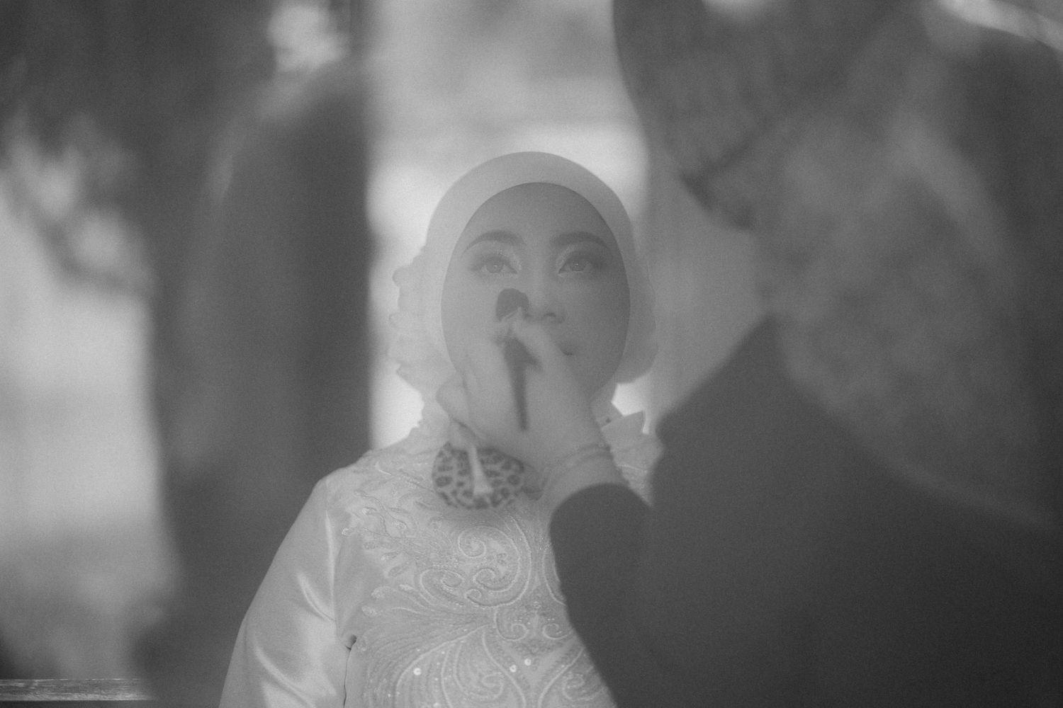 A bride in a white hijab and sparkly dress smiles during an intimate moment at a wedding ceremony.
