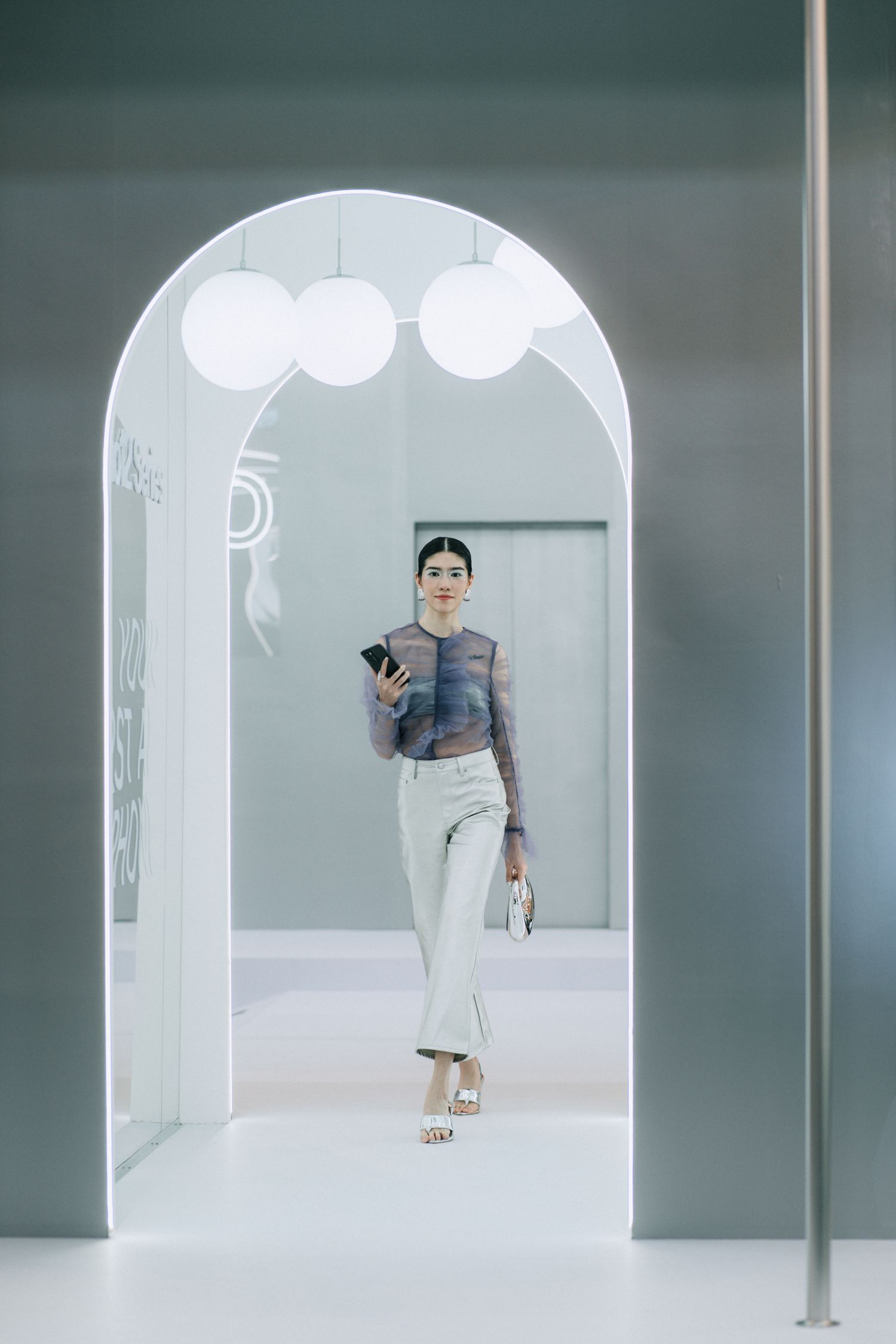 Modern retail space with an arched white doorway and hanging globe lights.
