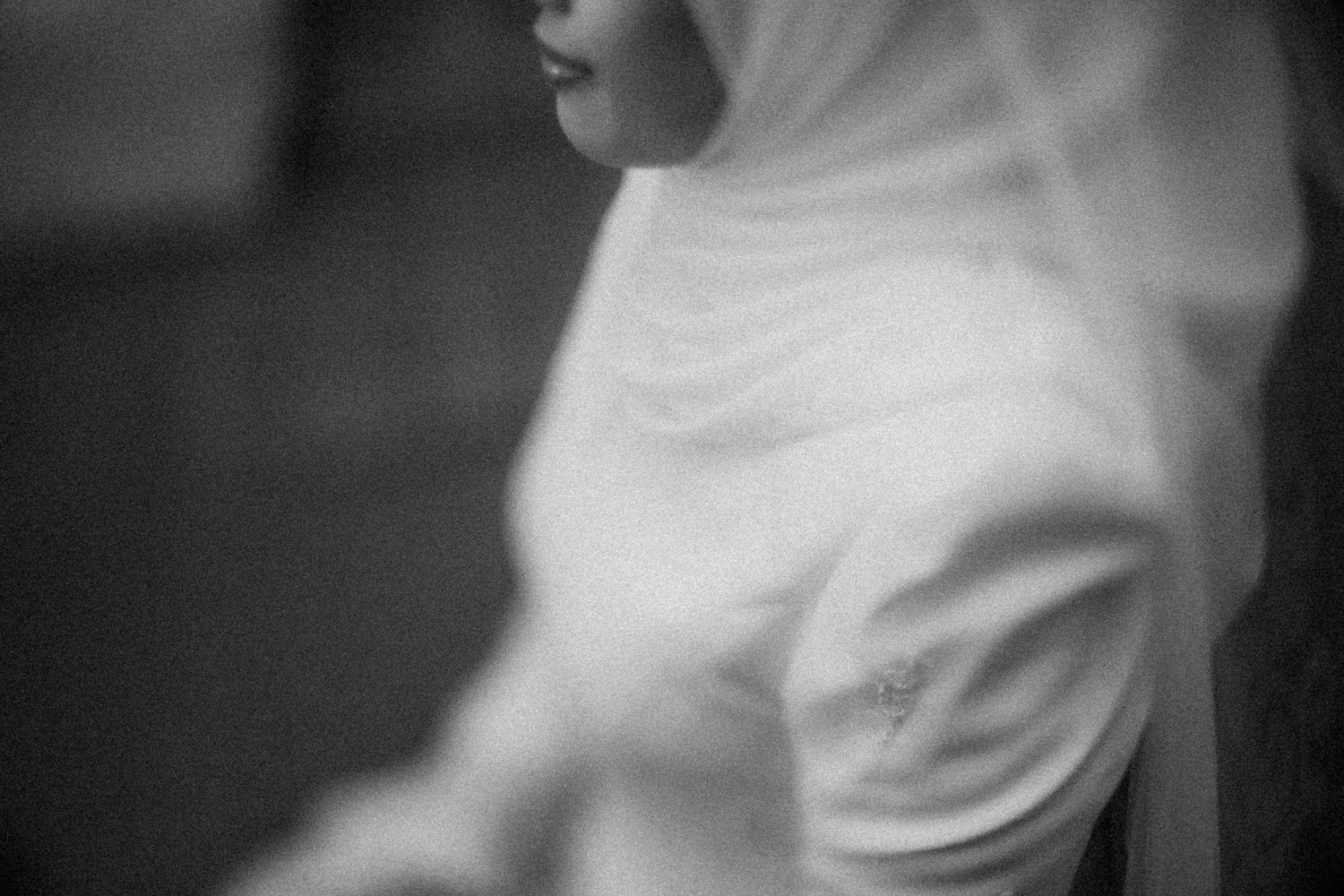 A black and white close-up photograph shows someone wearing a white t-shirt while looking off to the side.
