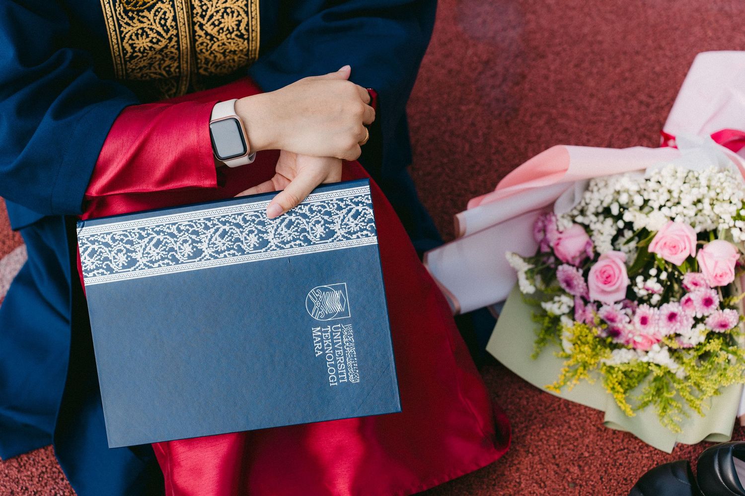 Close-up of decorated graduation diploma holder and pink flower bouquet.