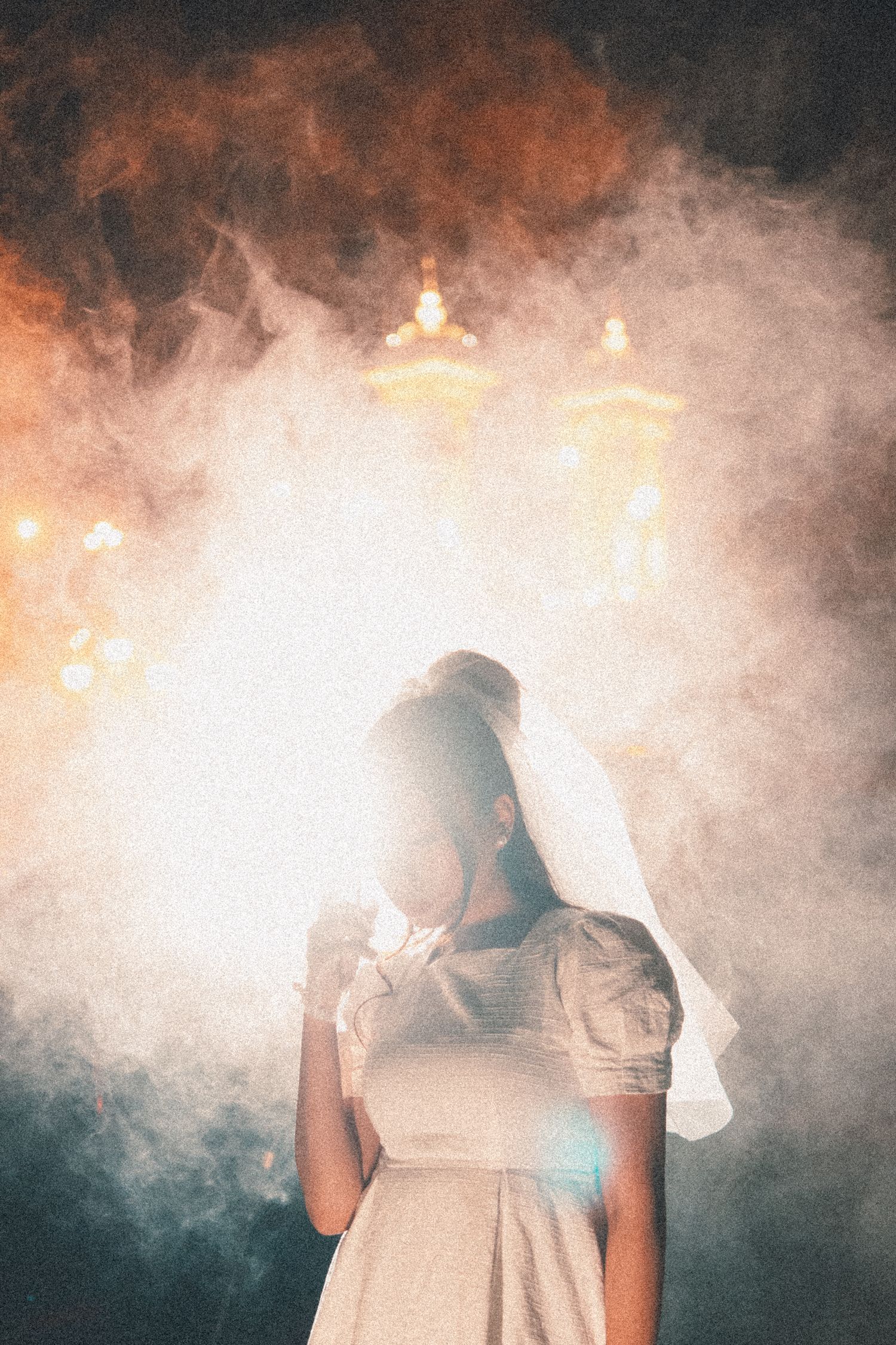 Atmospheric portrait with smoke and backlighting showing figure in white dress and veil.