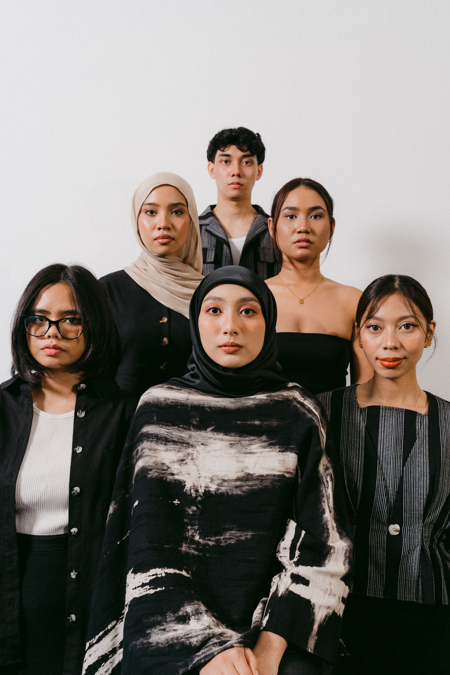 Fashion portrait of diverse group in modern black and white attire against light background.