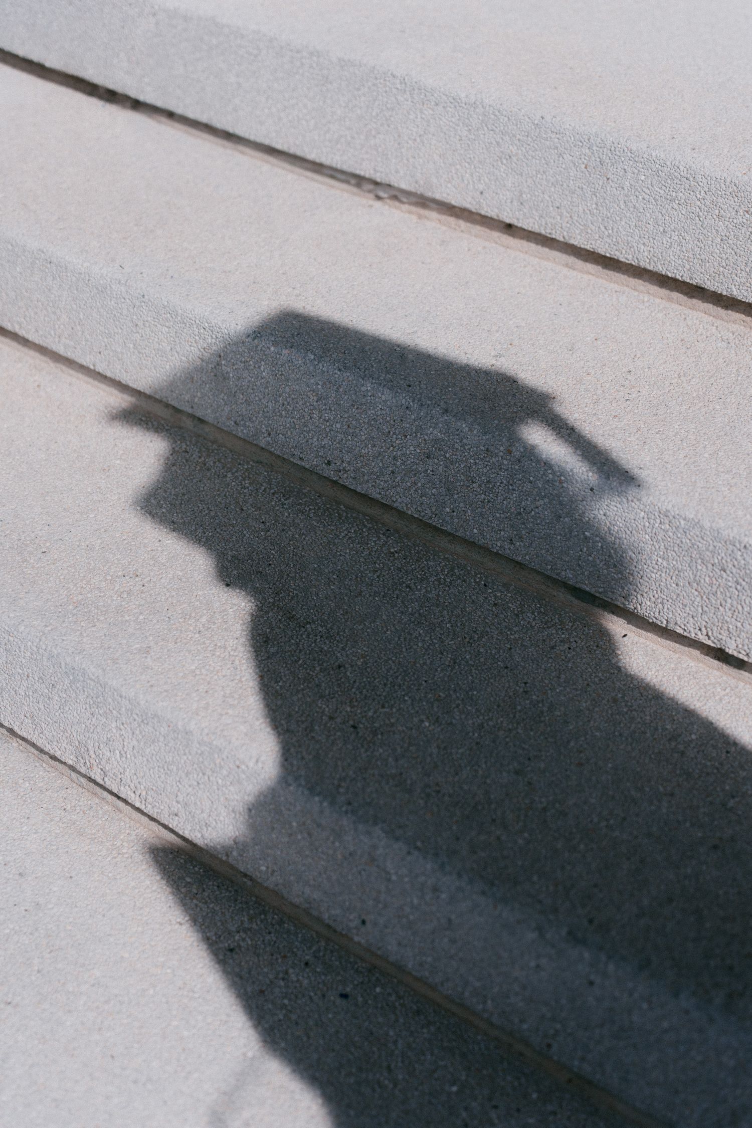 A sequence of shadow silhouettes cast on white wooden planks showing a person's profile from different angles.