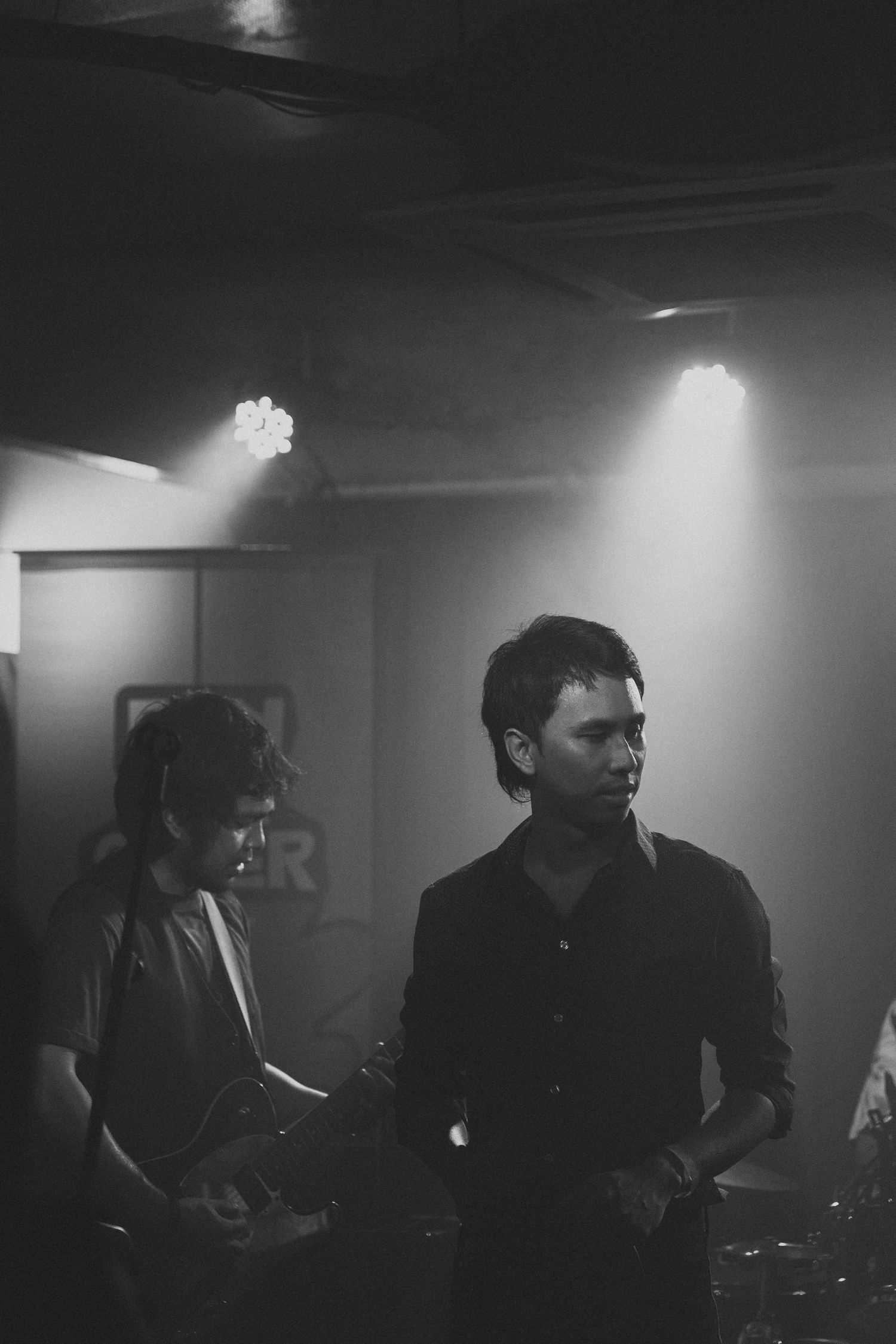 Dramatic black and white series of atmospheric band members performing in moody lighting onstage.