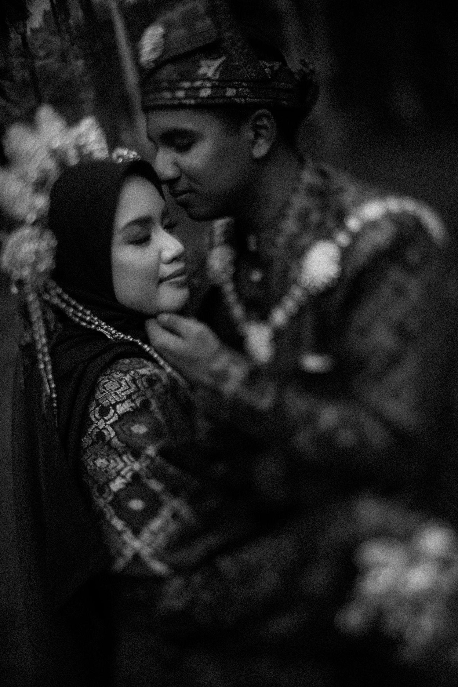 A romantic black and white portrait of a couple in traditional Ukrainian embroidered outfits embracing outdoors.