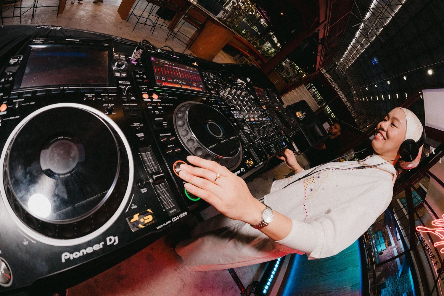Professional DJ equipment setup with turntables and mixers in a nightclub setting during a performance.