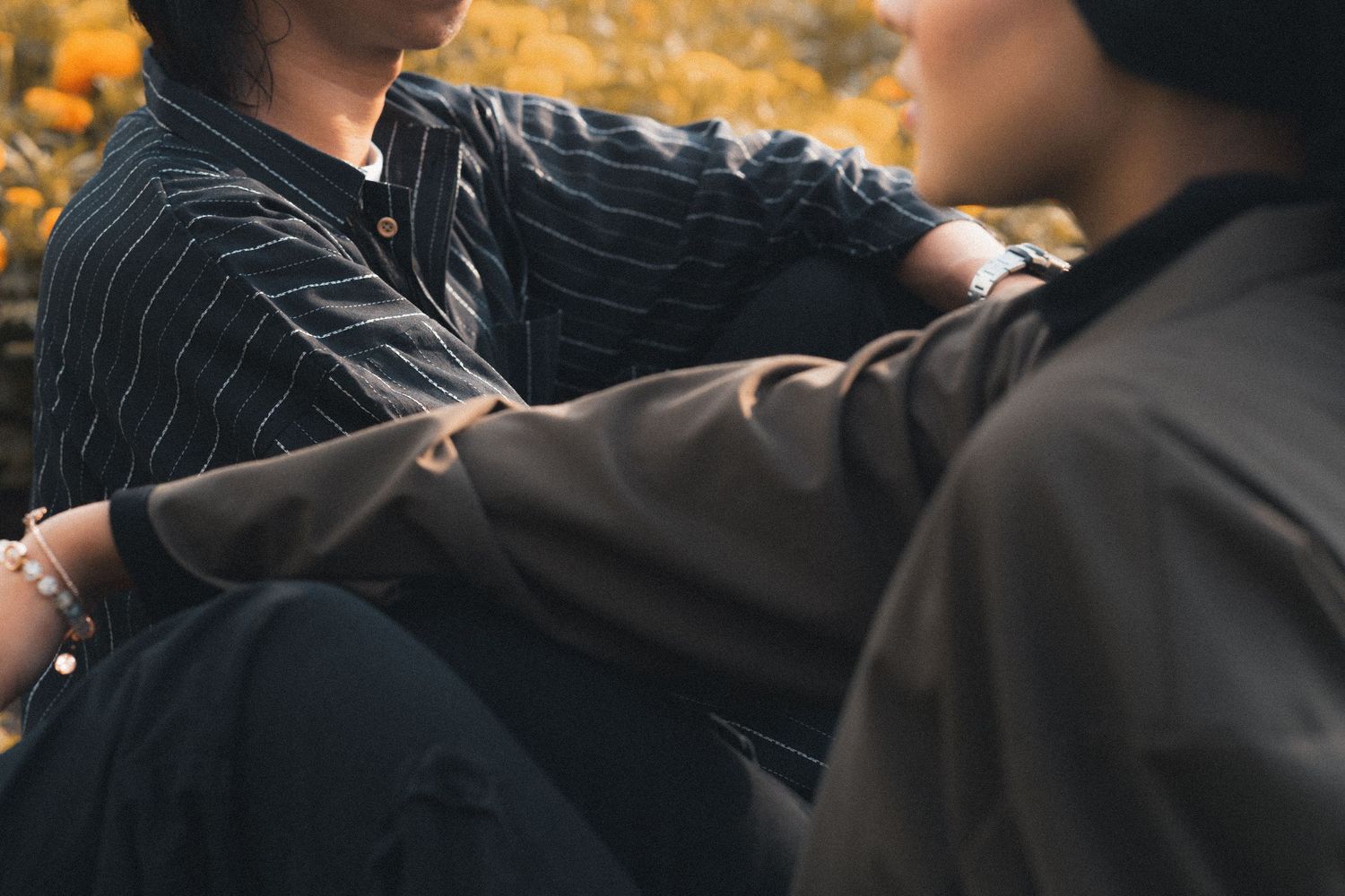 Intimate moment captured between two people in casual wear among autumn foliage.